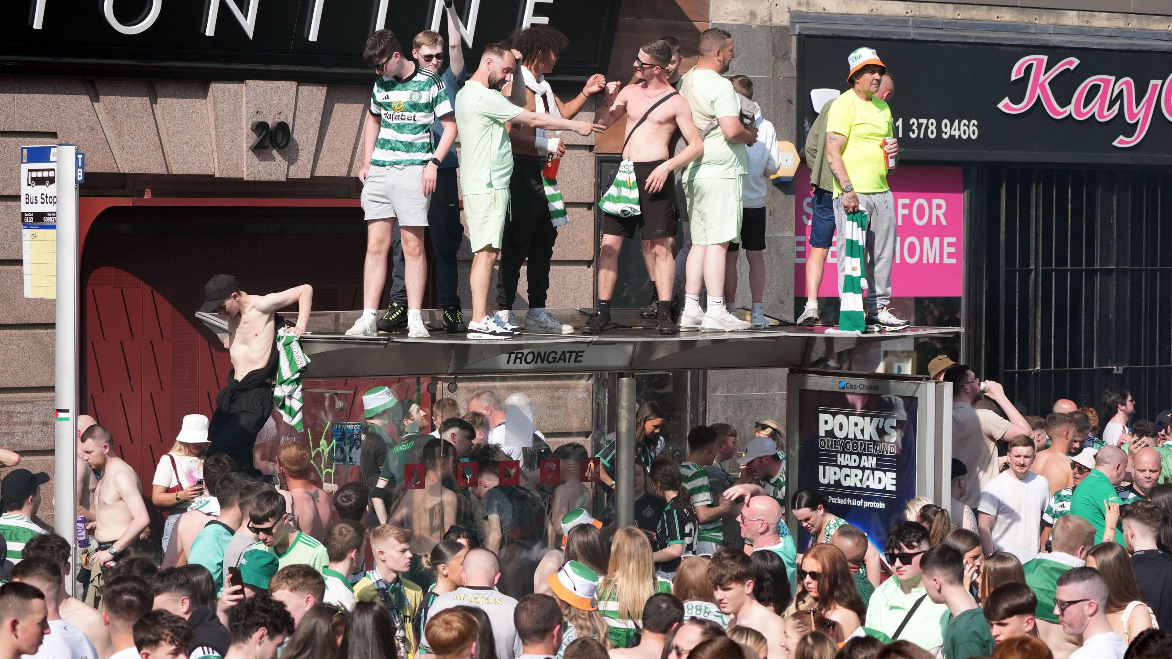 Crowd of football fans with some standing on top of a bus stop