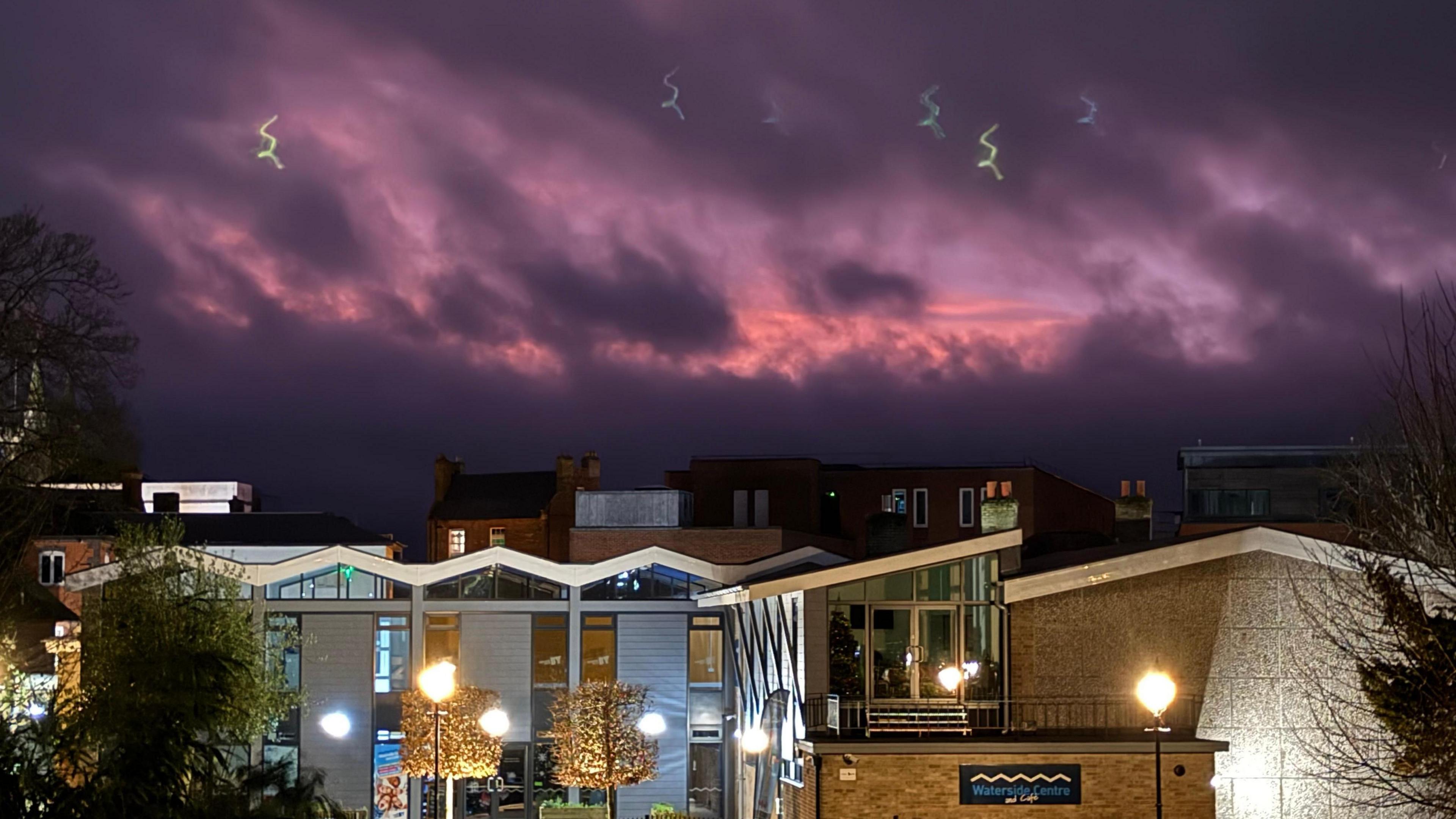 A dark purple sky over several buildings. One has a sign on that says 'Waterside Centre'. Within the sky there is also shades of pink.