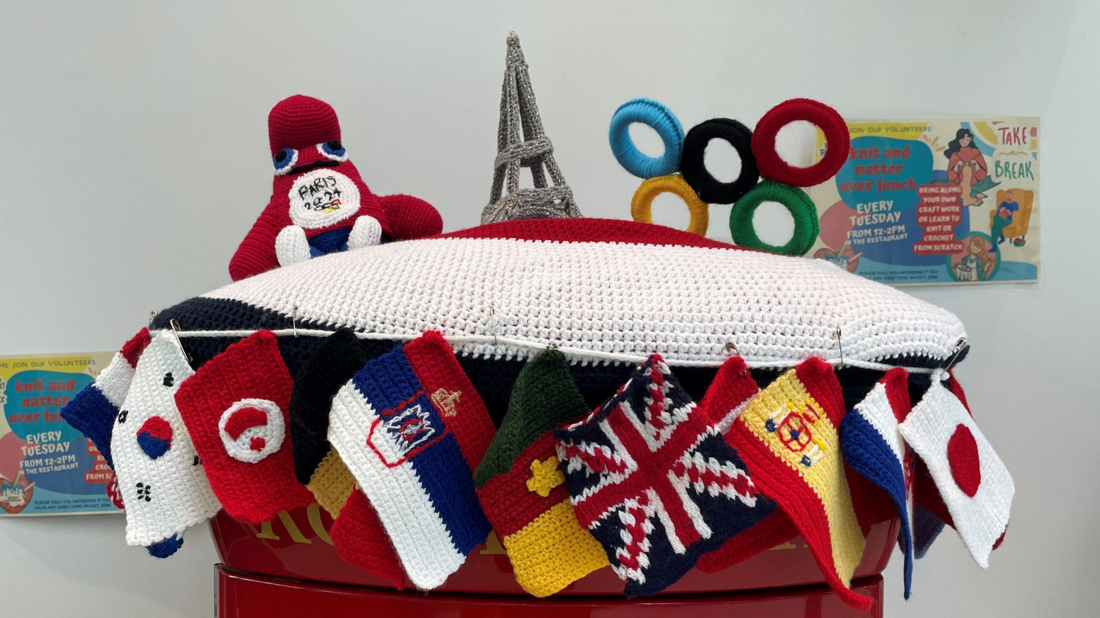 A stitched post box topper with colourful flags, the Eiffel Tower, the Olympic rings and 2024 mascot.