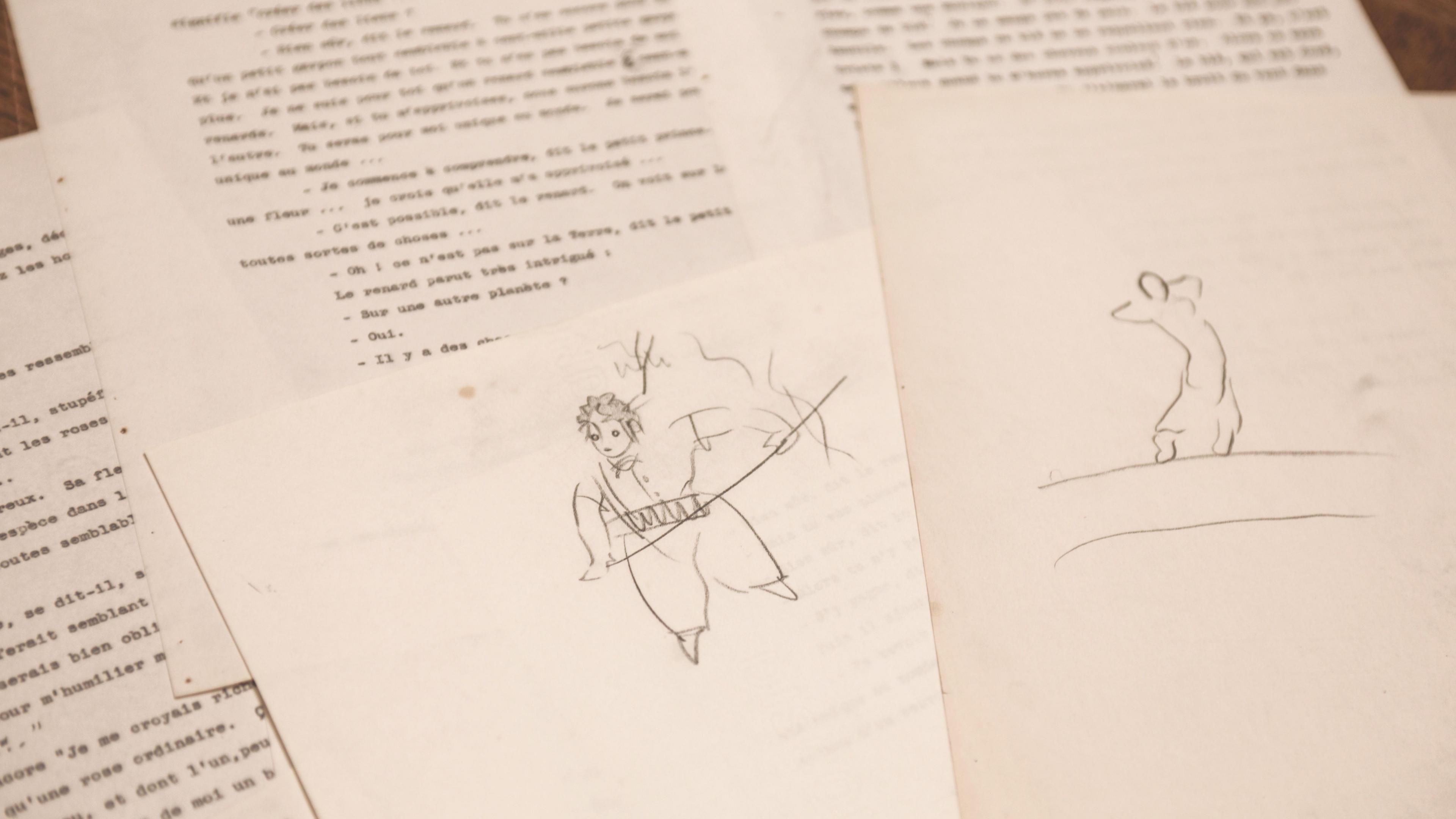 Two sketches of people on paper lay on top of typescript