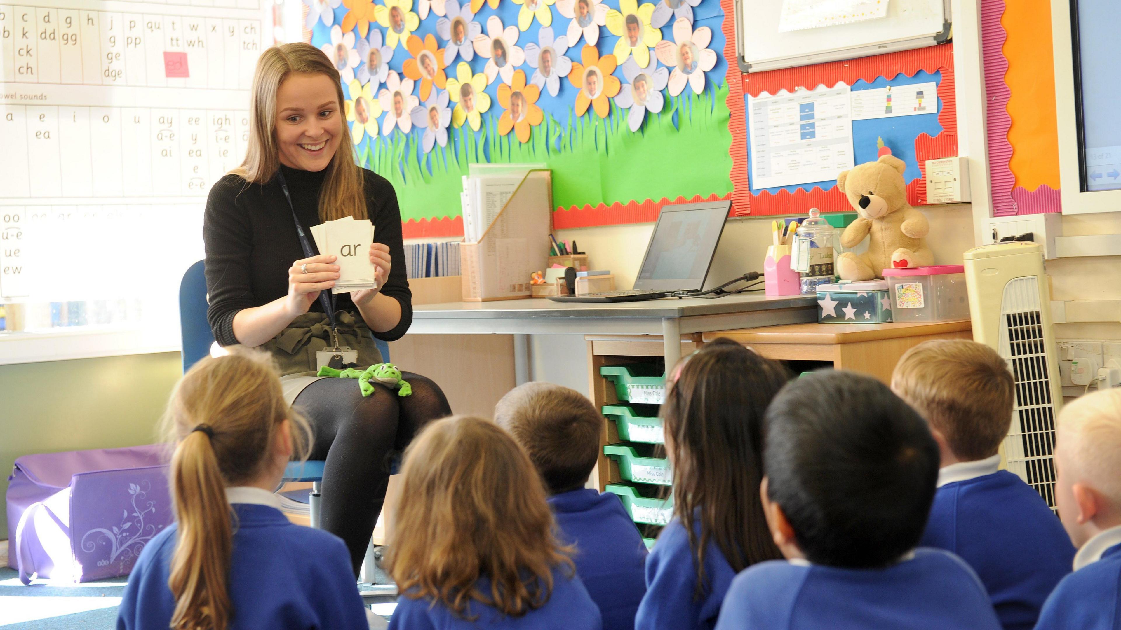 Teacher Alice Cole teaching phonics to her class. She is sitting on her chair and the students are watching her teach the 'ar' sound