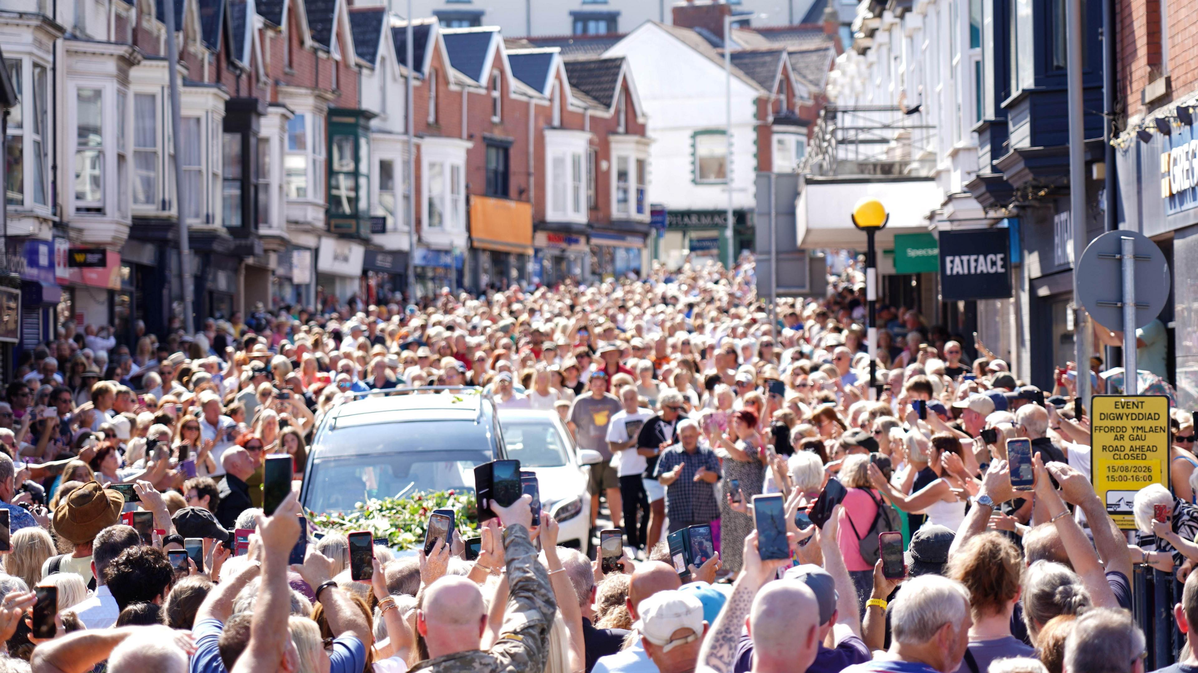 Thousands of fans gathered in the street as Bonnie Tyler's coffin drives down the road in a black funeral car.
