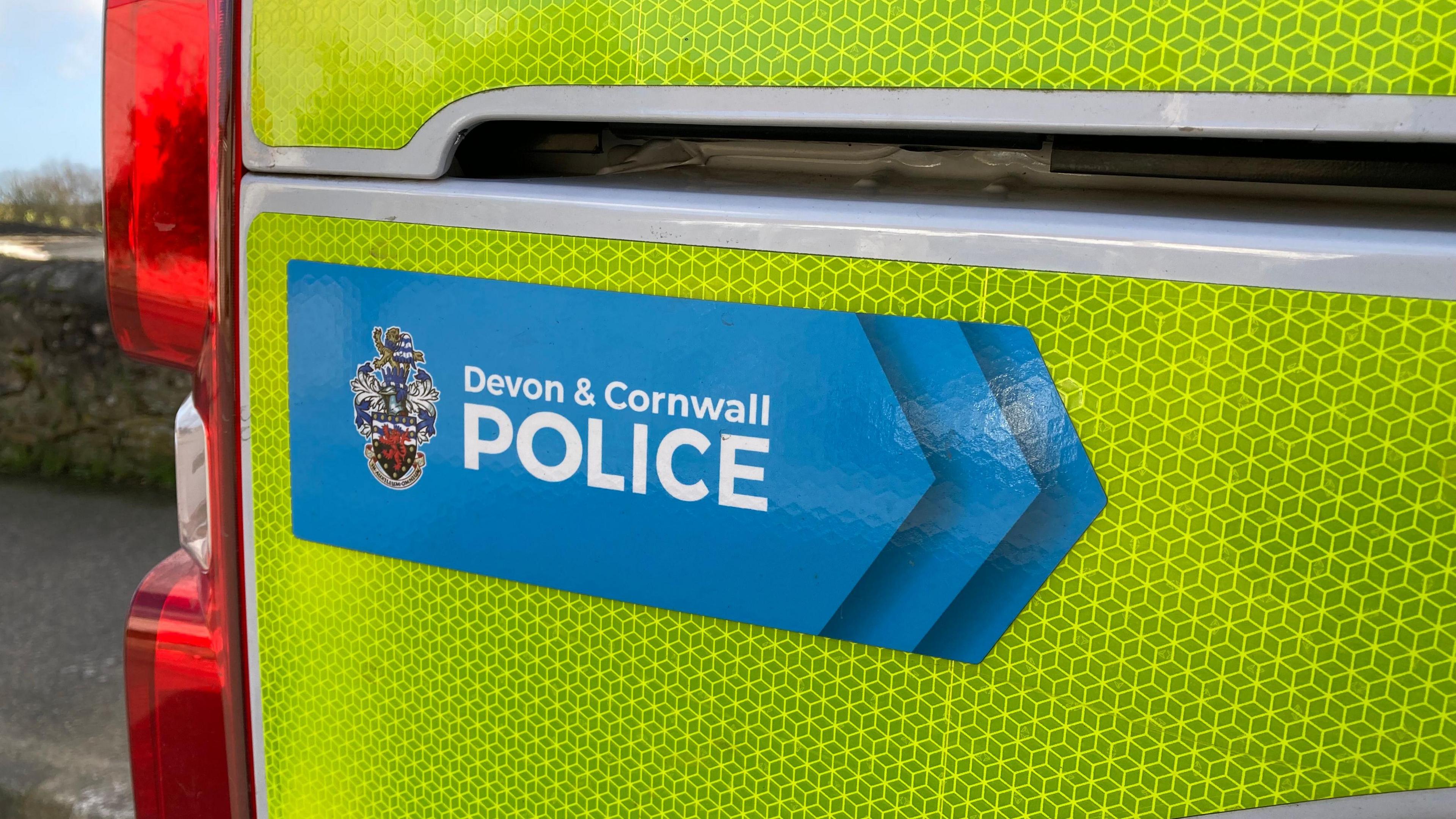The side of a neon yellow police van with the Devon & Cornwall Police logo and emblem.