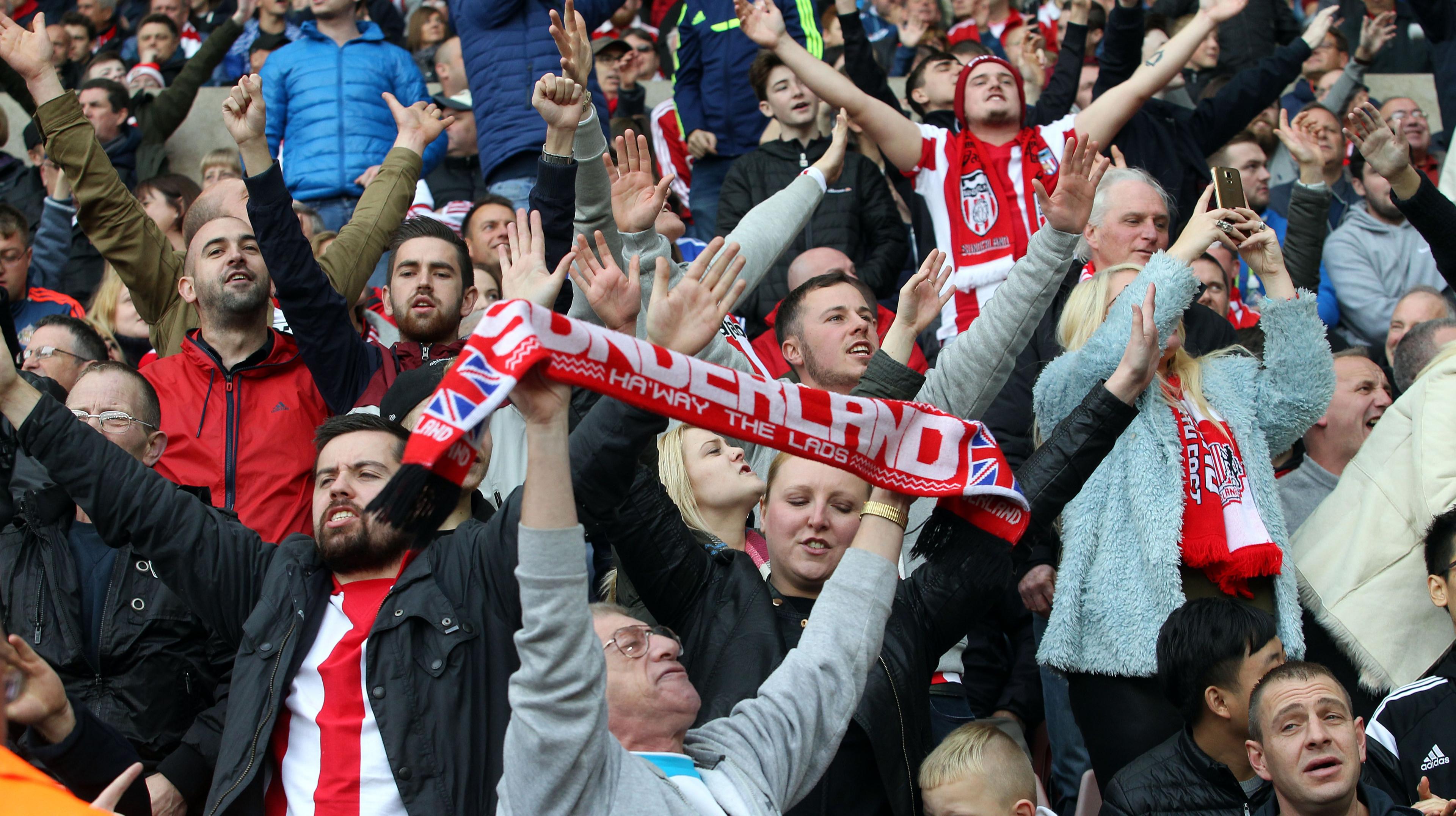 Sunderland fans holding up scarves and stretching their arms out wide in the stands