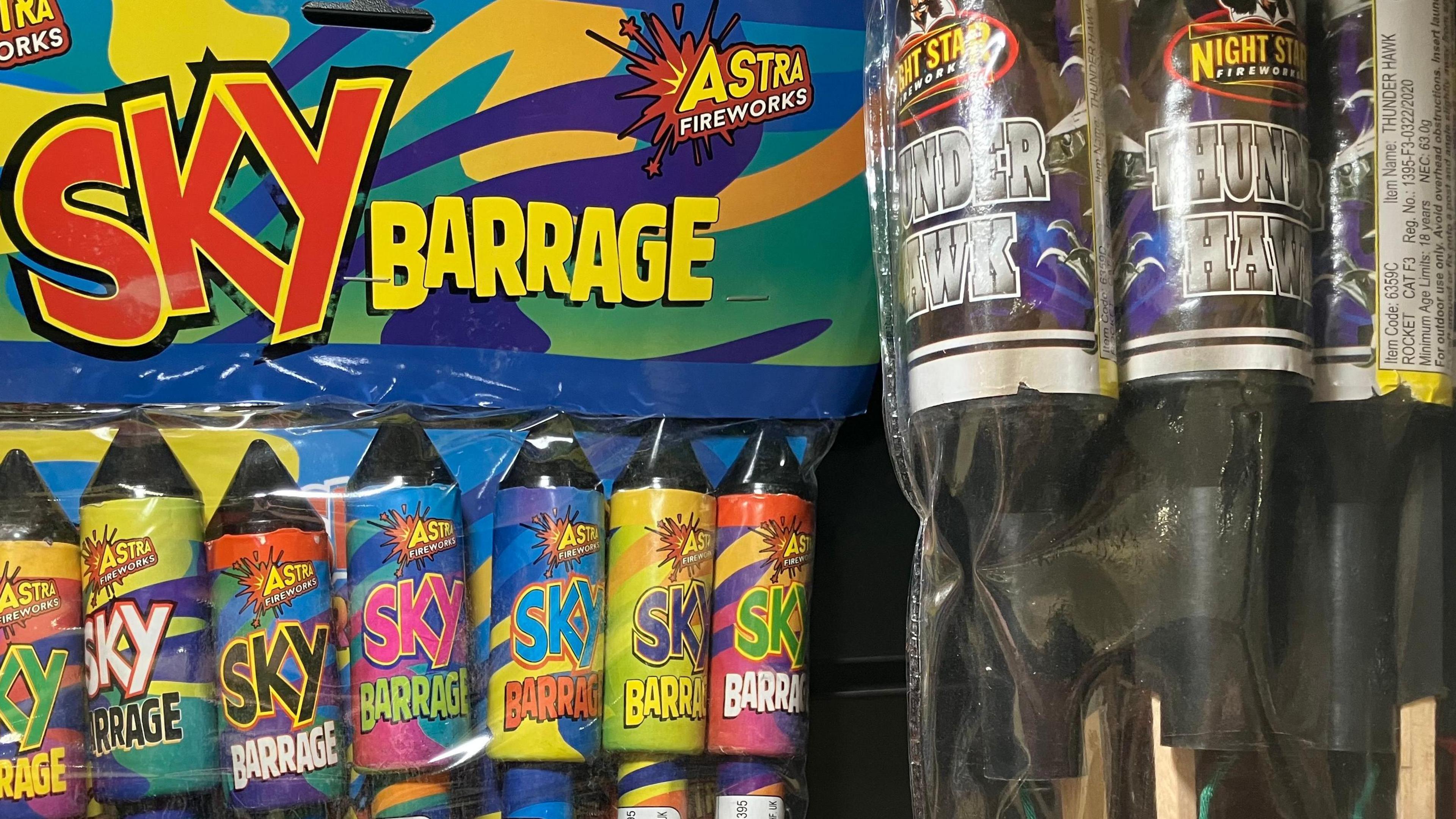 A case with fireworks in them, there are two in view called Sky Barrage and Thunder Hawk which have bright and colourful packaging.