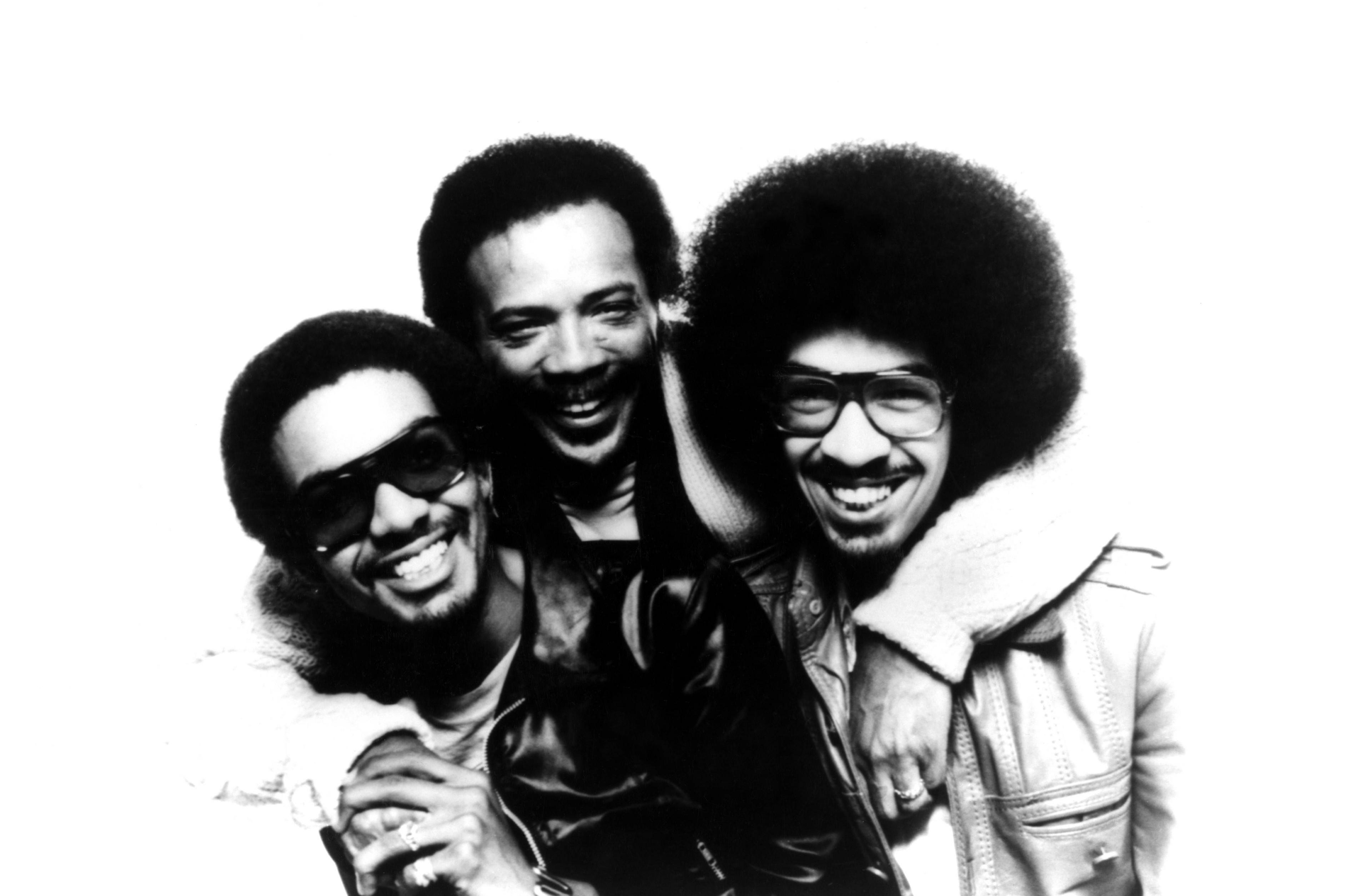 Louis Johnson, Quincy Jones and George Johnson smile at the camera as they embrace