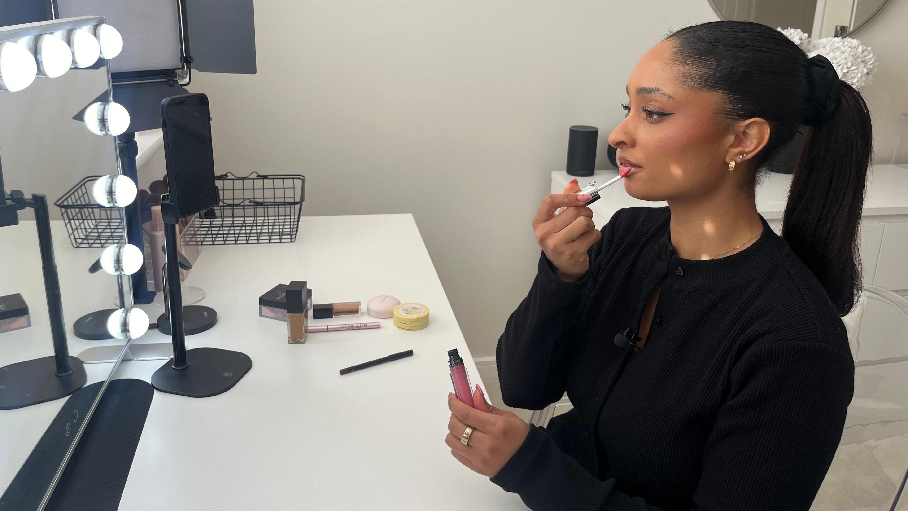 Leila Nikea applying make-up in front of a mirror