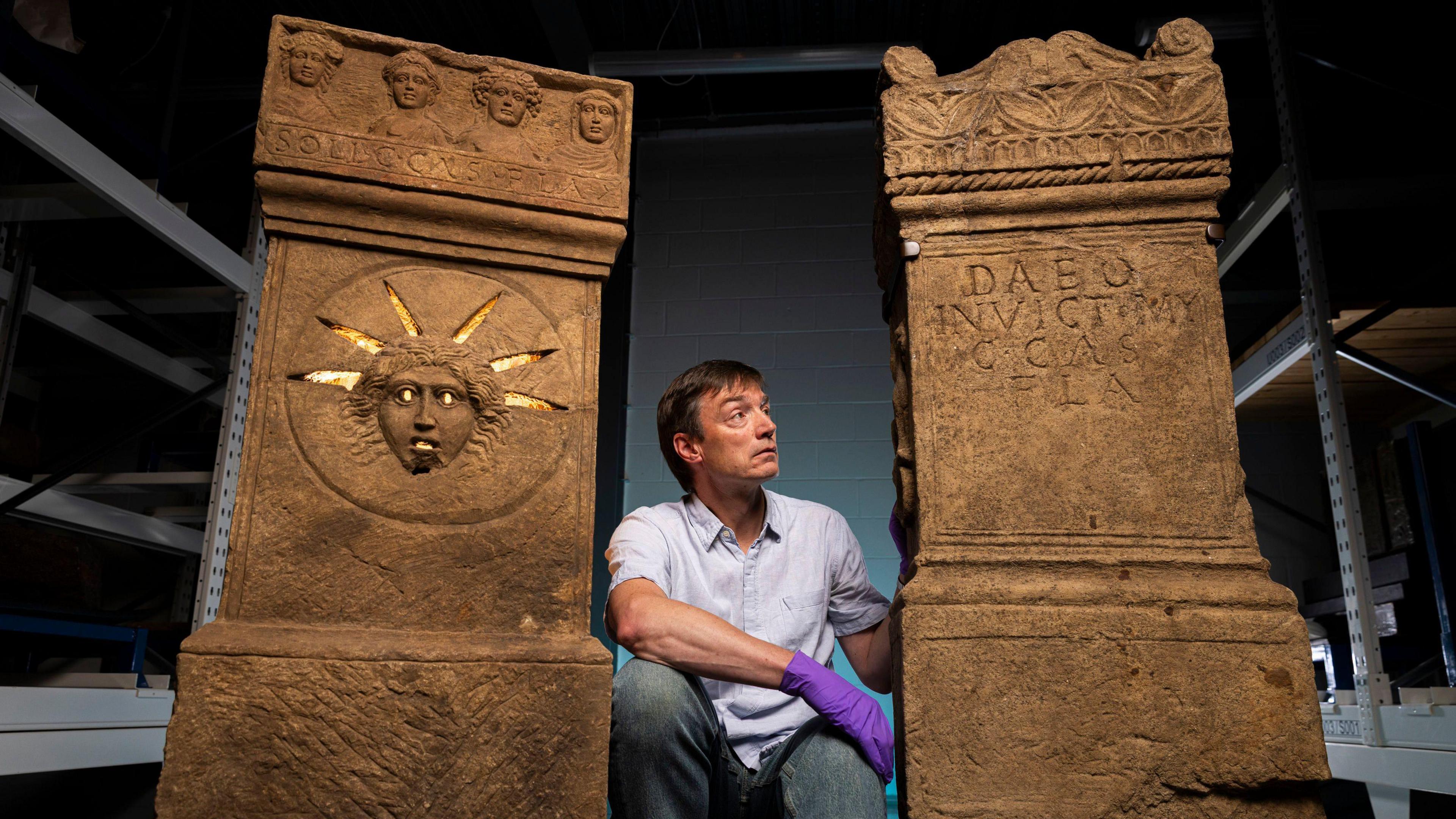 A curator crouching between two pillars