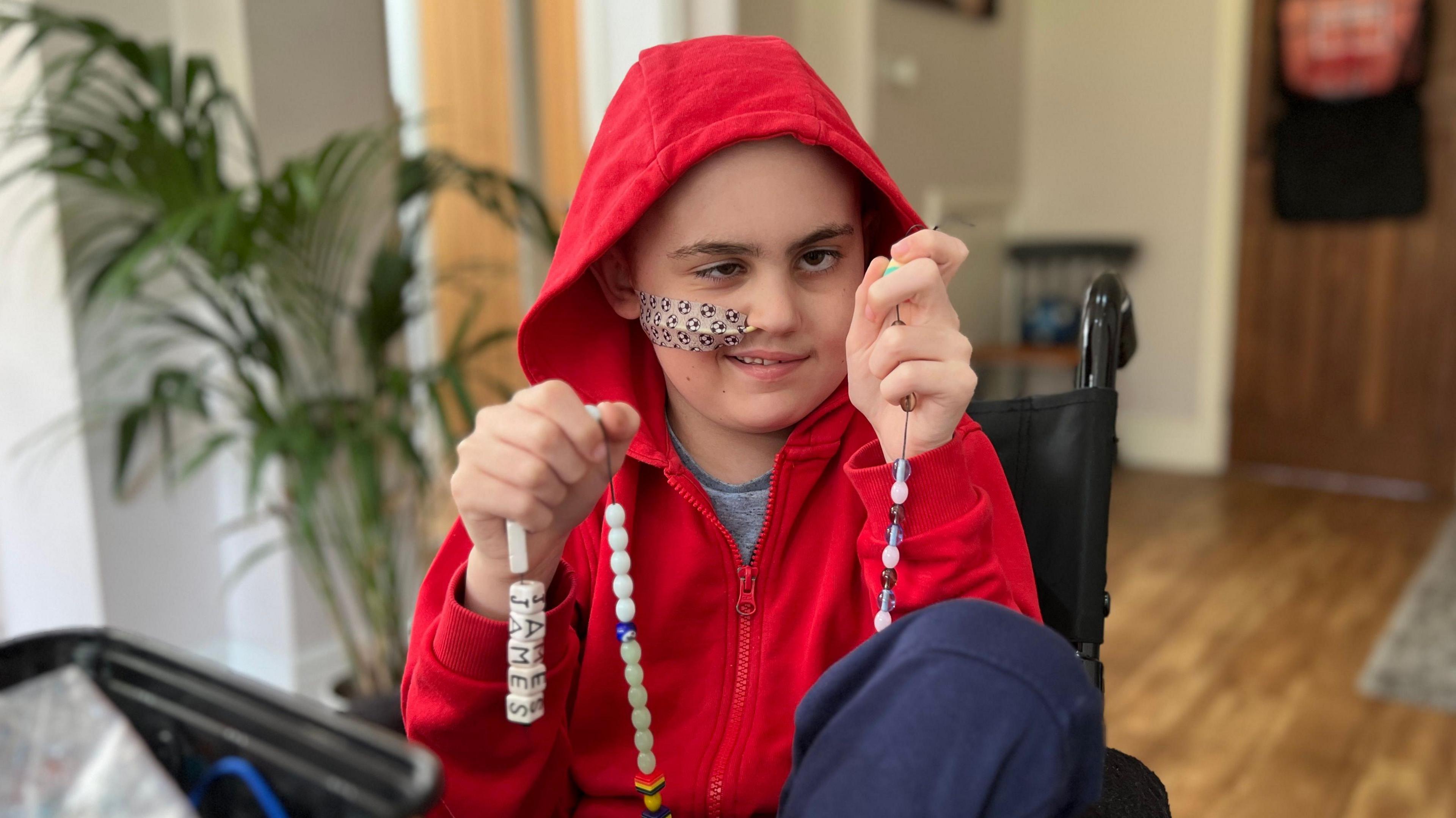 James sitting at home making bracelets