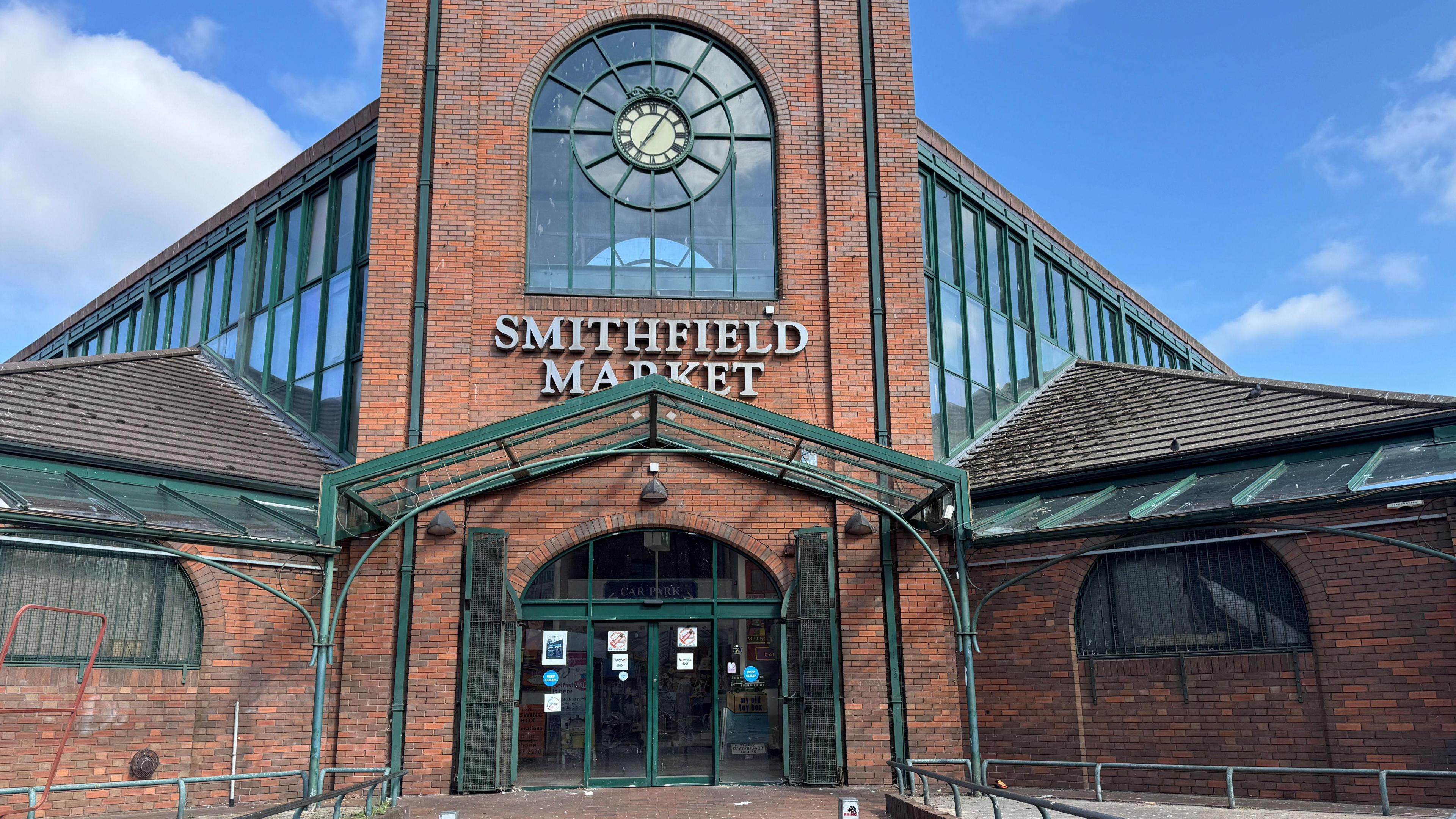 The exterior of Smithfield Market. It is a red brick building with green trim