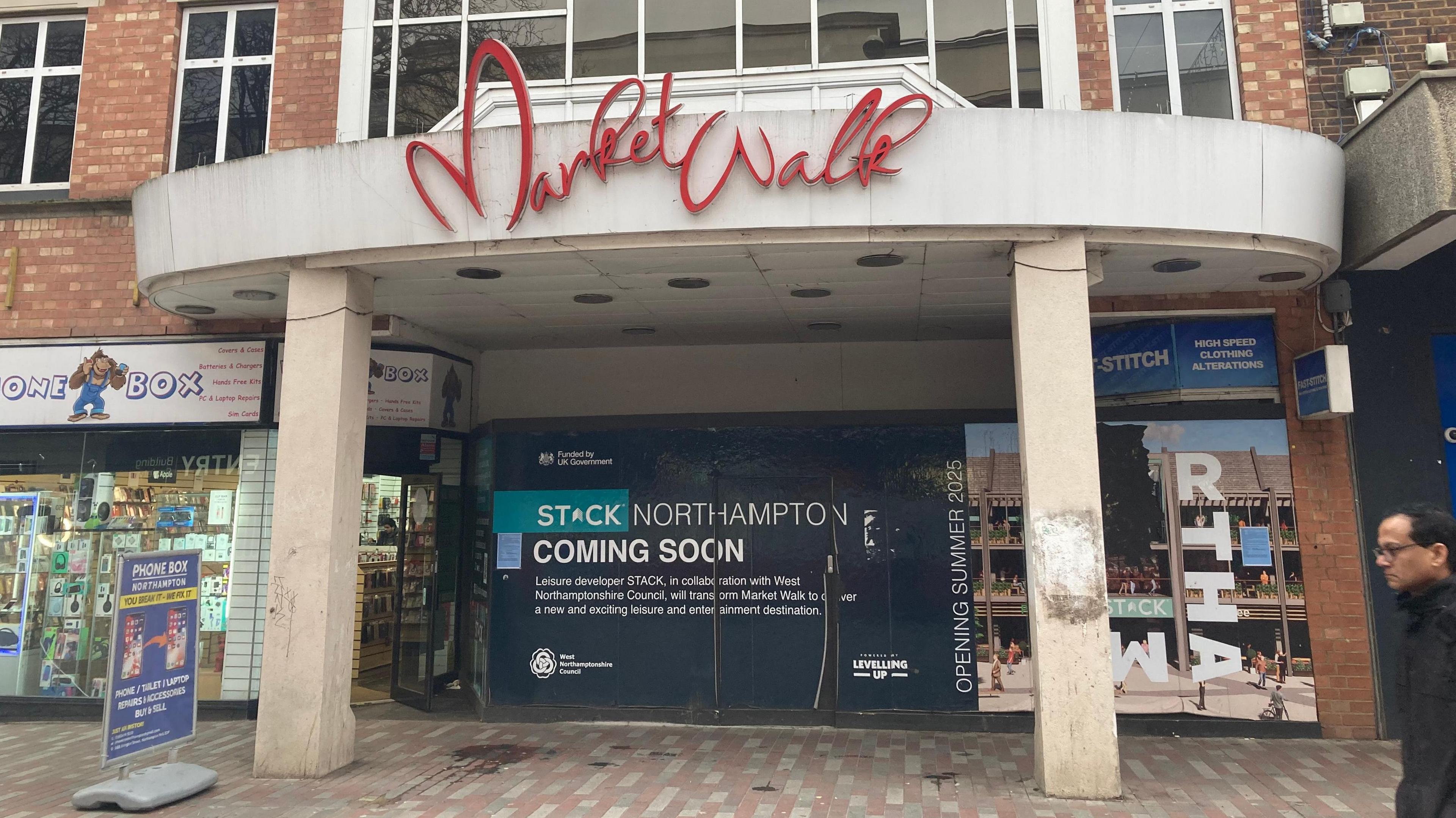 Abington Street entrance to the former Market Place shopping centre. The entrance is boarded up with an advert for Stack which it says is "coming soon". 