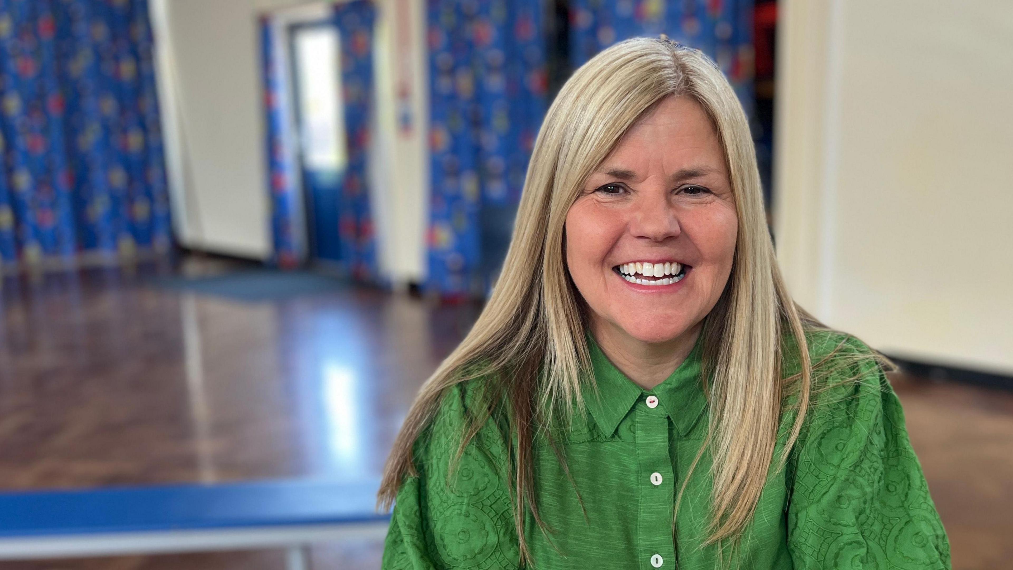 A smiling woman inside a school hall