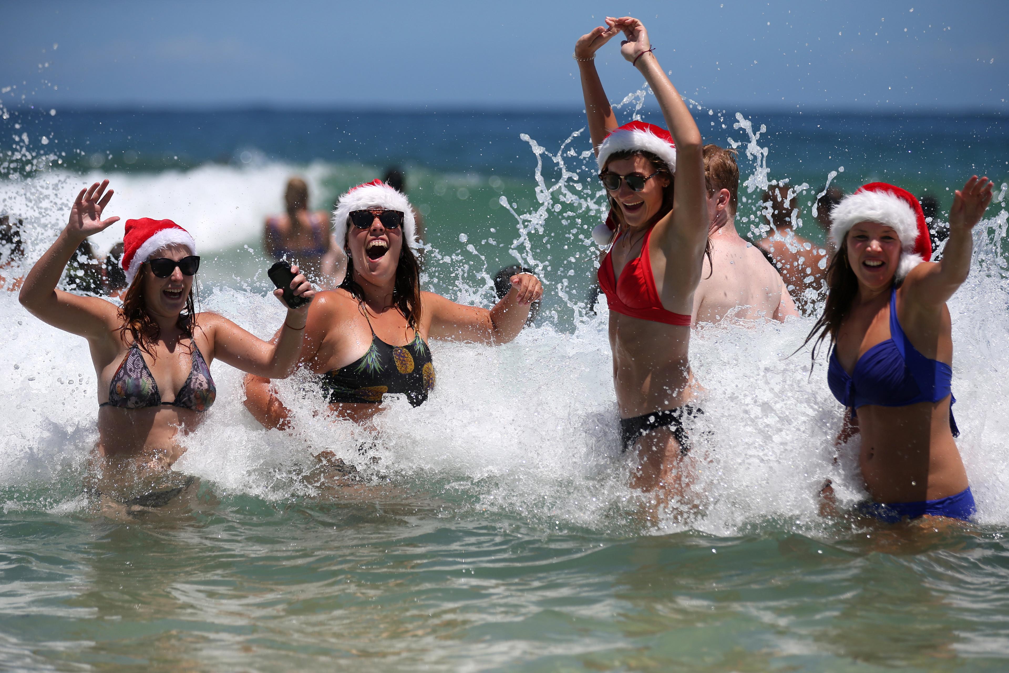 Marlies Noordeloos of the Netherlands, left, Lisa Van De Velde of Belgium, second left, Charlotte Trotter of Britain, second right, and Viktoria Sardarian of Lithuania wear Santa hats while in the surf at Bondi Beach celebrating Christmas Day in Sydney, Australia, Friday, Dec. 25, 2015