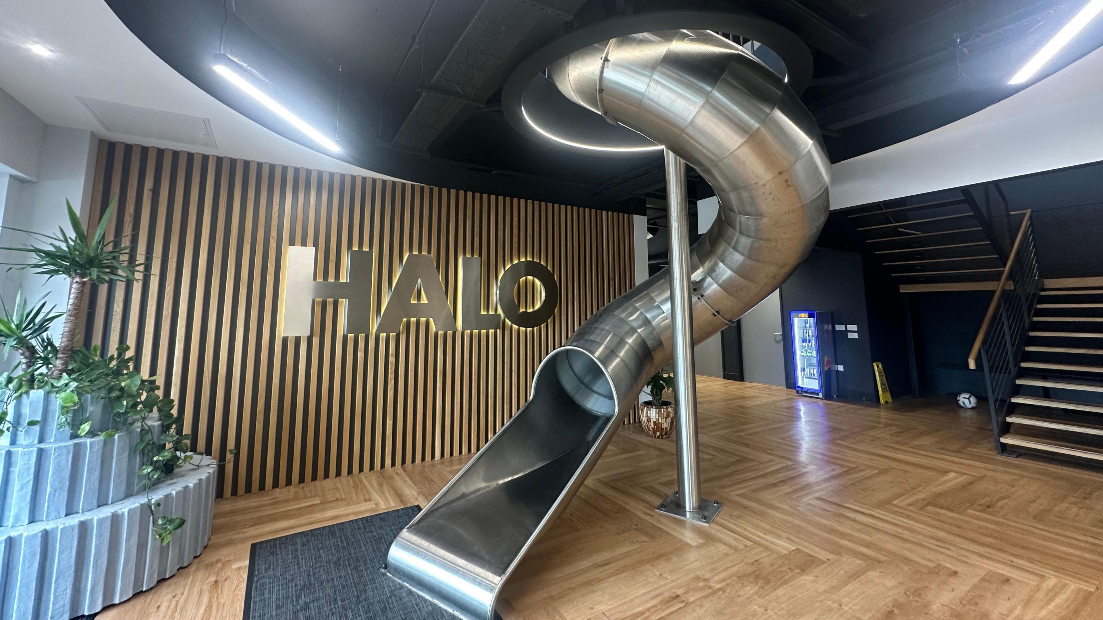 The silver metal slide in Halo's office entrance. The company's logo and name rests on a wall behind the slide. 