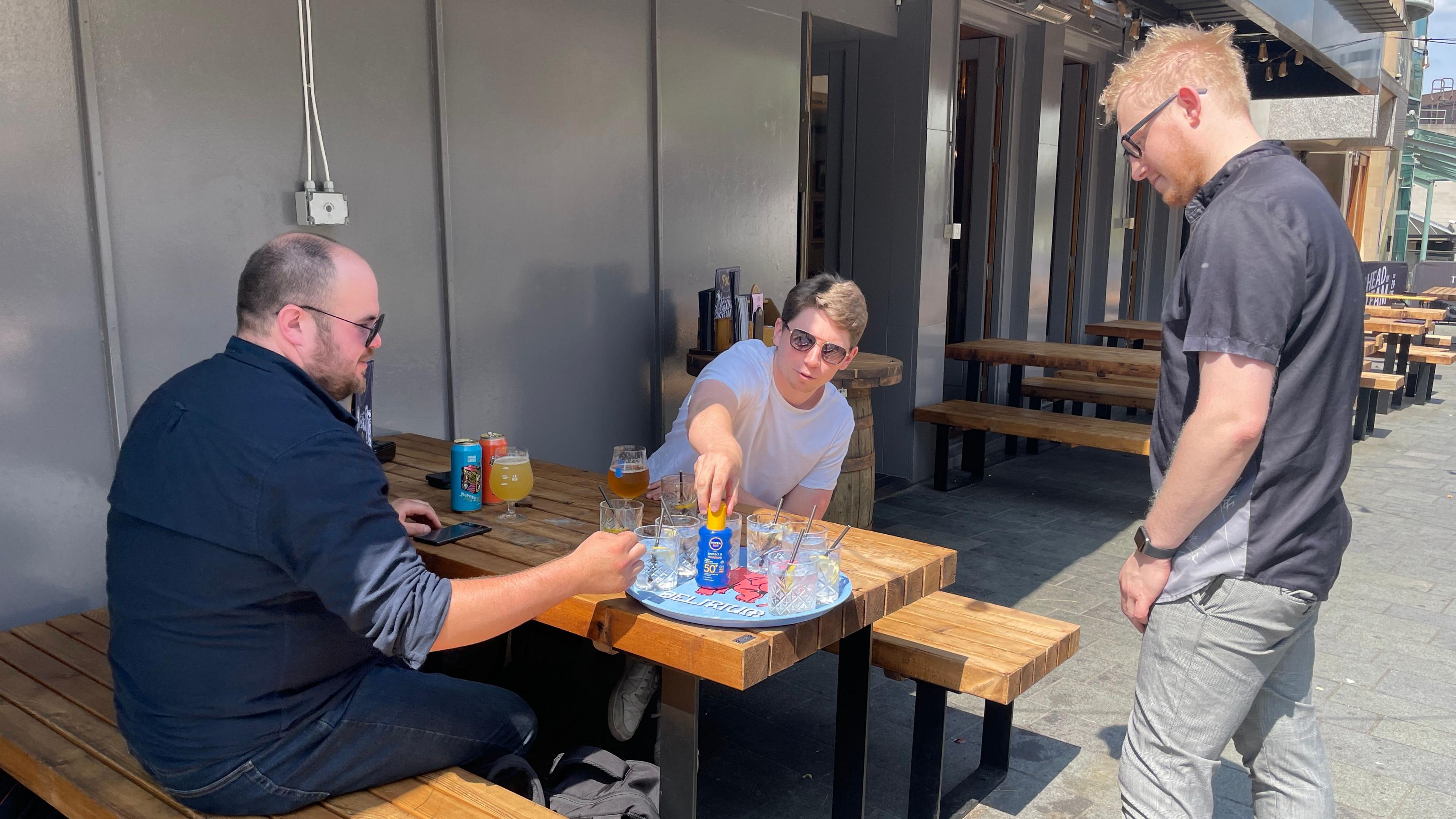 Customer Graeme Hunt, 31, reaching for the suncream while he sits on a picnic bench in the beer garden of The Head of Steam pub in Sheffield.