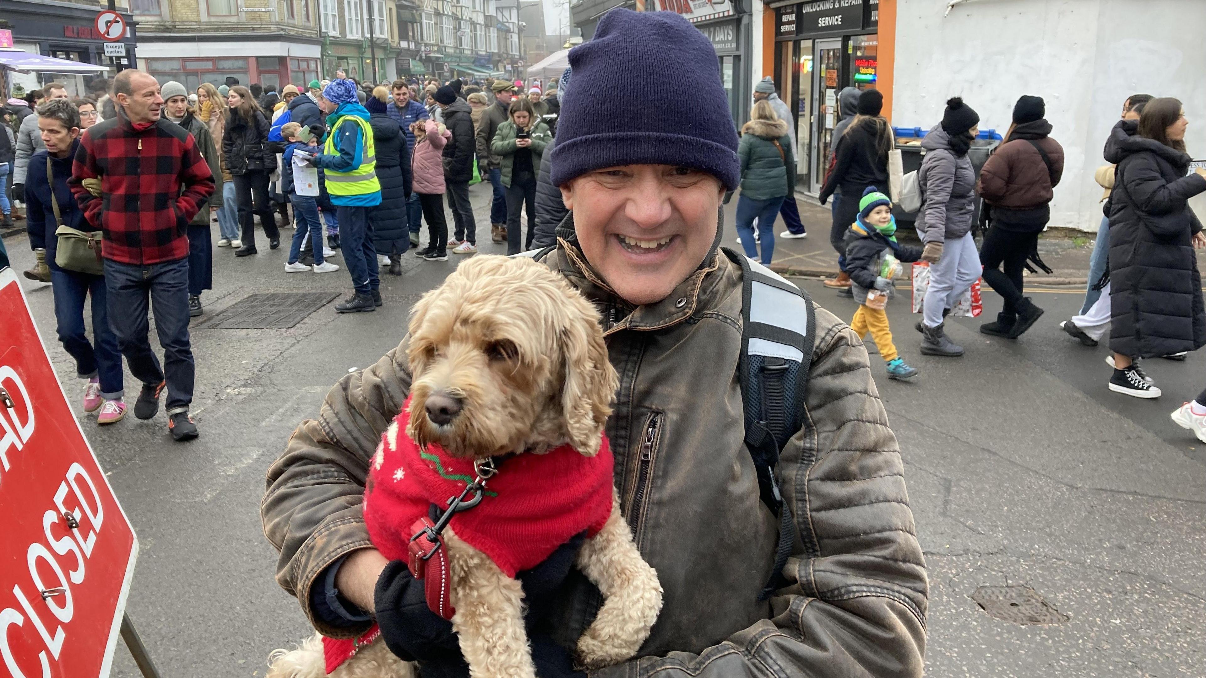 A man and a dog in a red cardigan