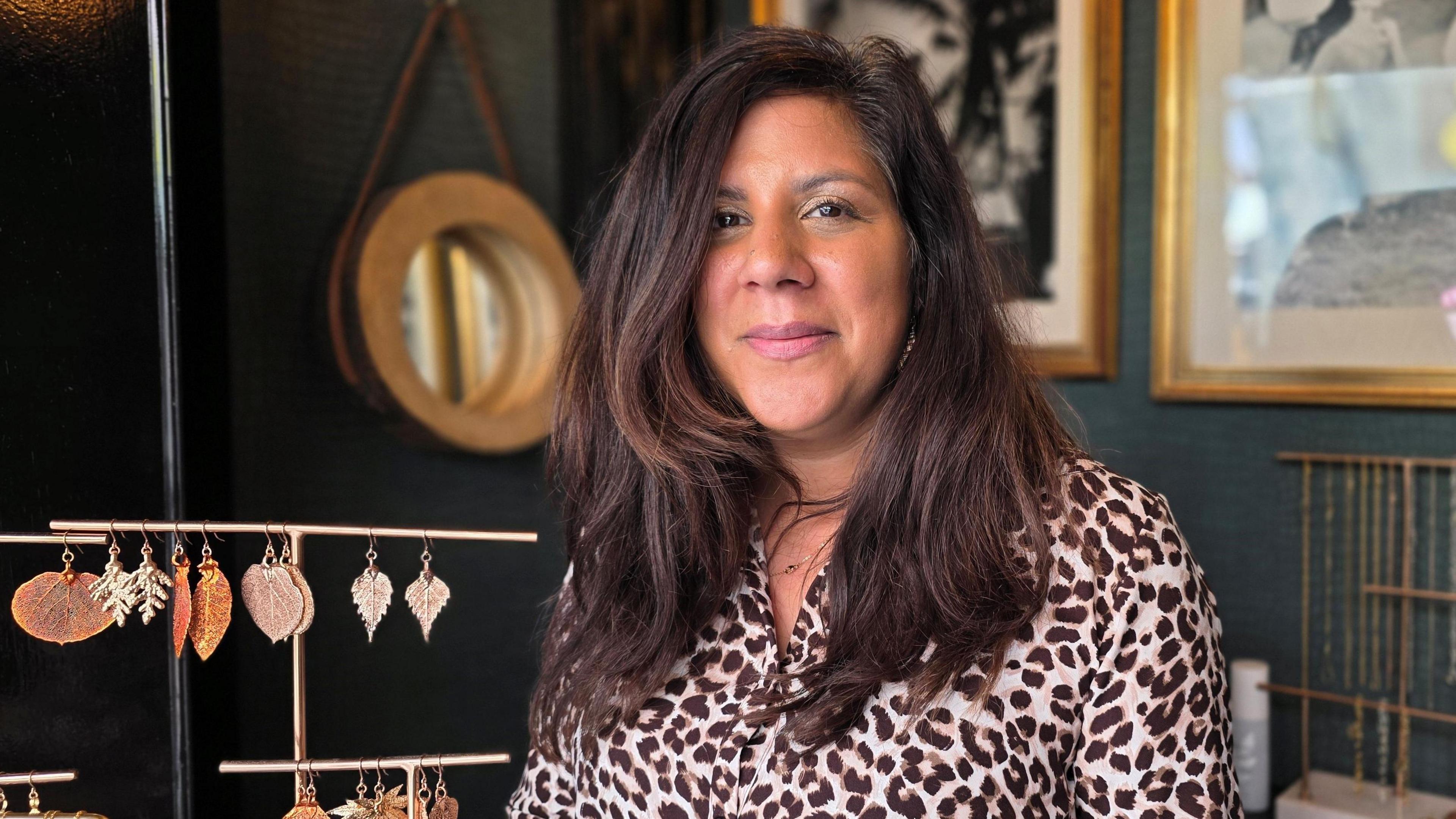 Sophie is wearing a light leopard print-type top. Some of her jewellery - gold leaves - is to her side.