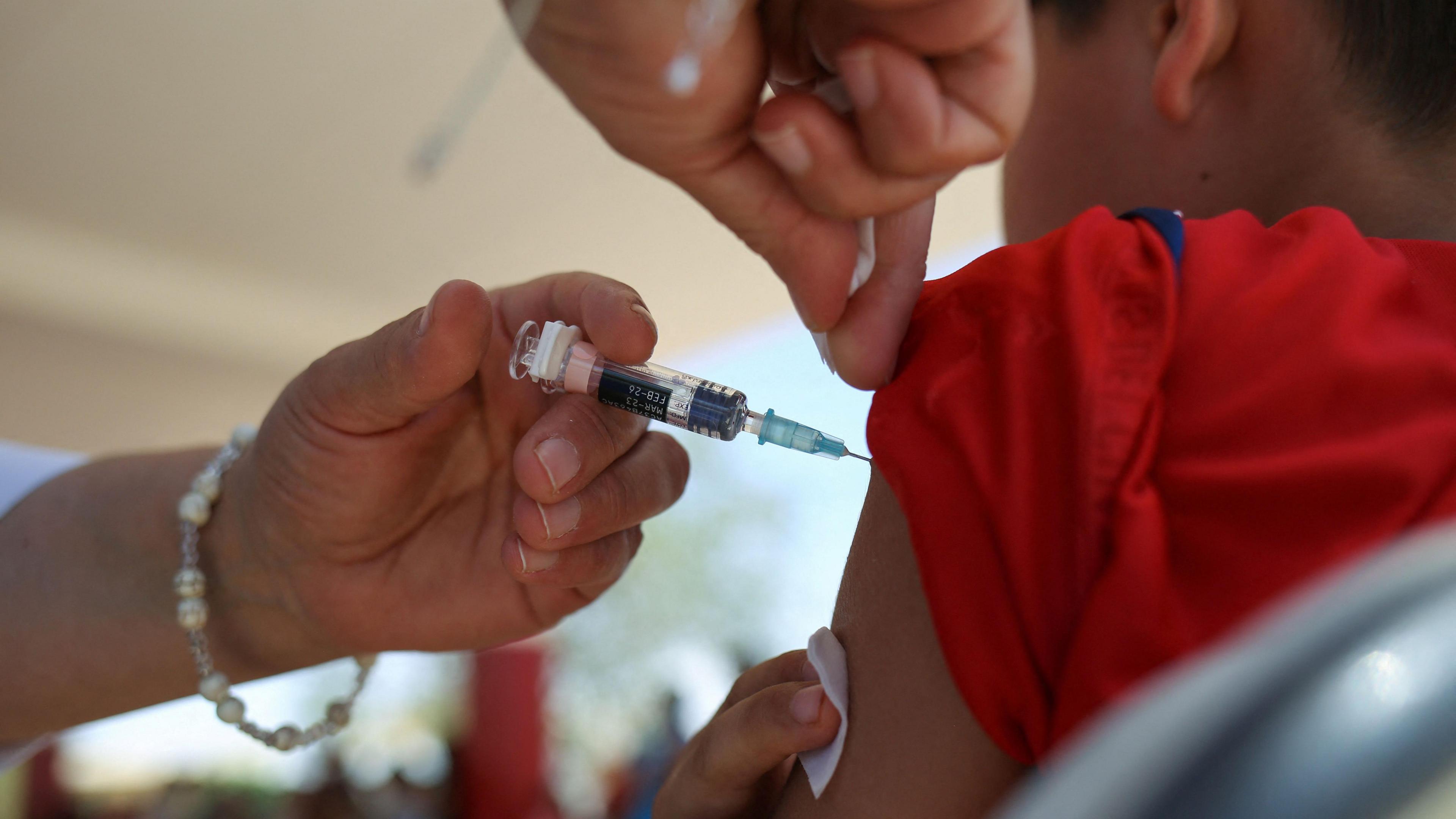 A young boy gets an injection in his arm.