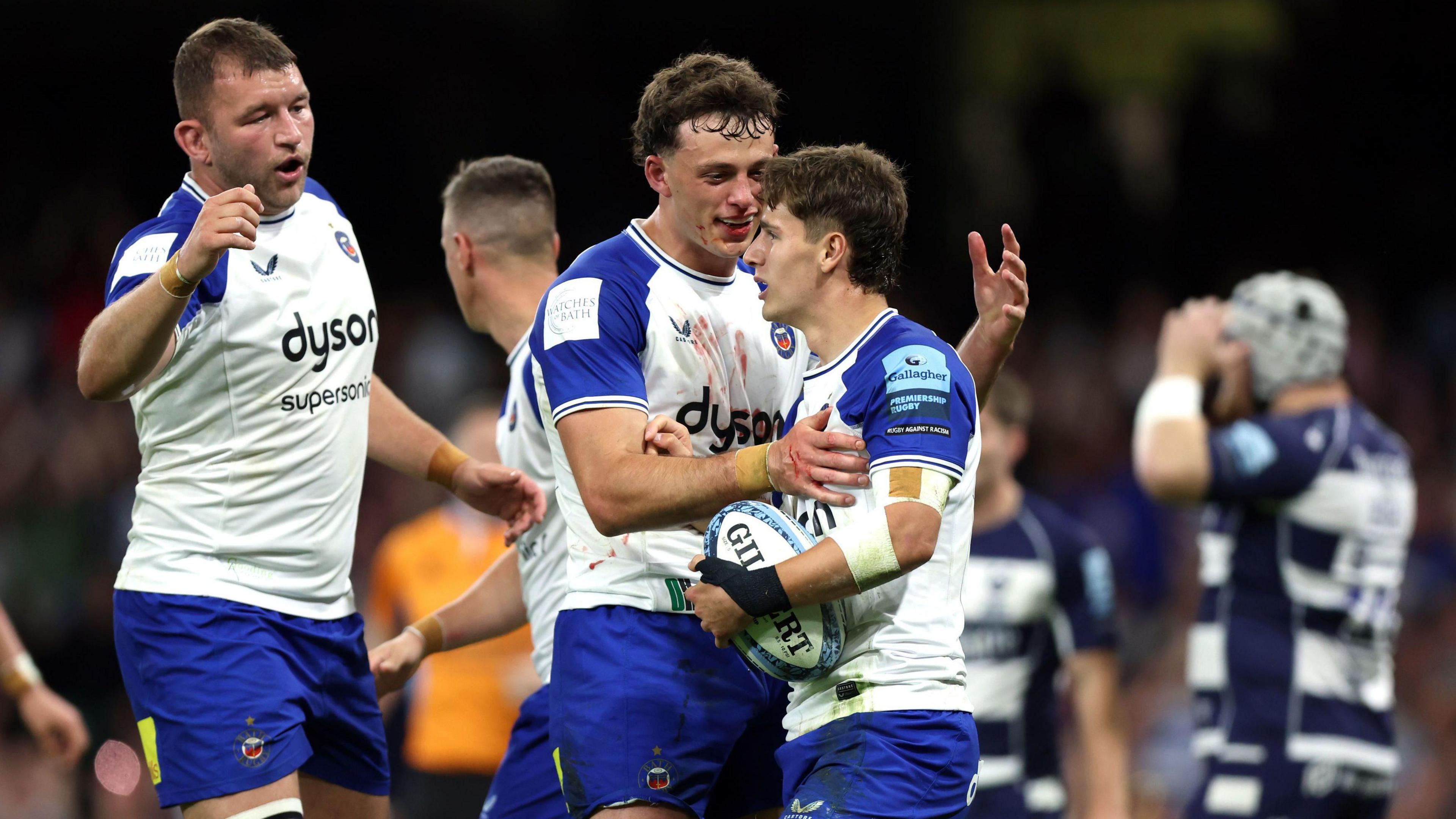 Bath players in their change kit of white with blue sleeves congratulate their try scorer during the match with Bristol at the Principality Stadium in Cardiff