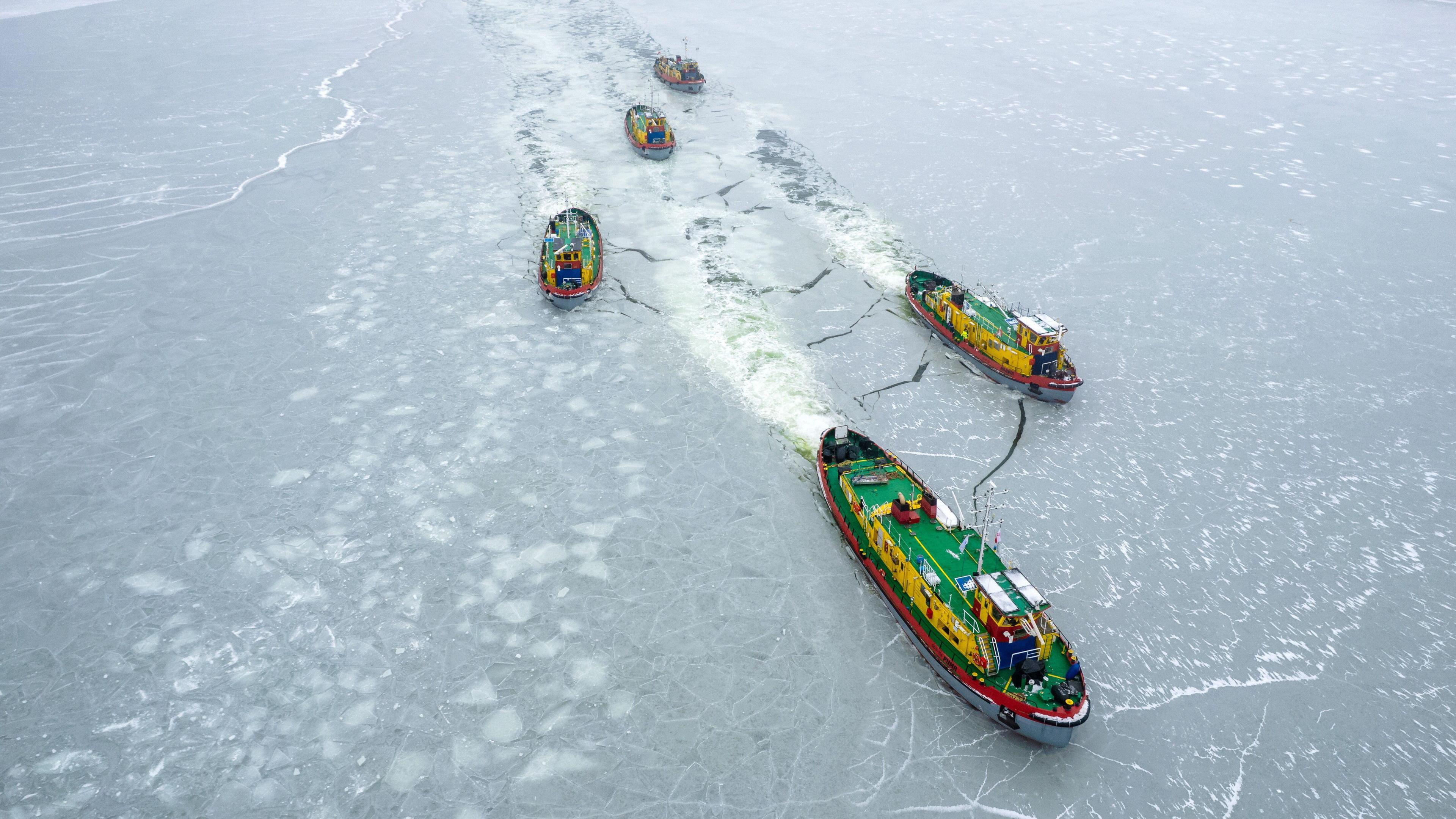Five colourful icebreaker boats on a frozen river