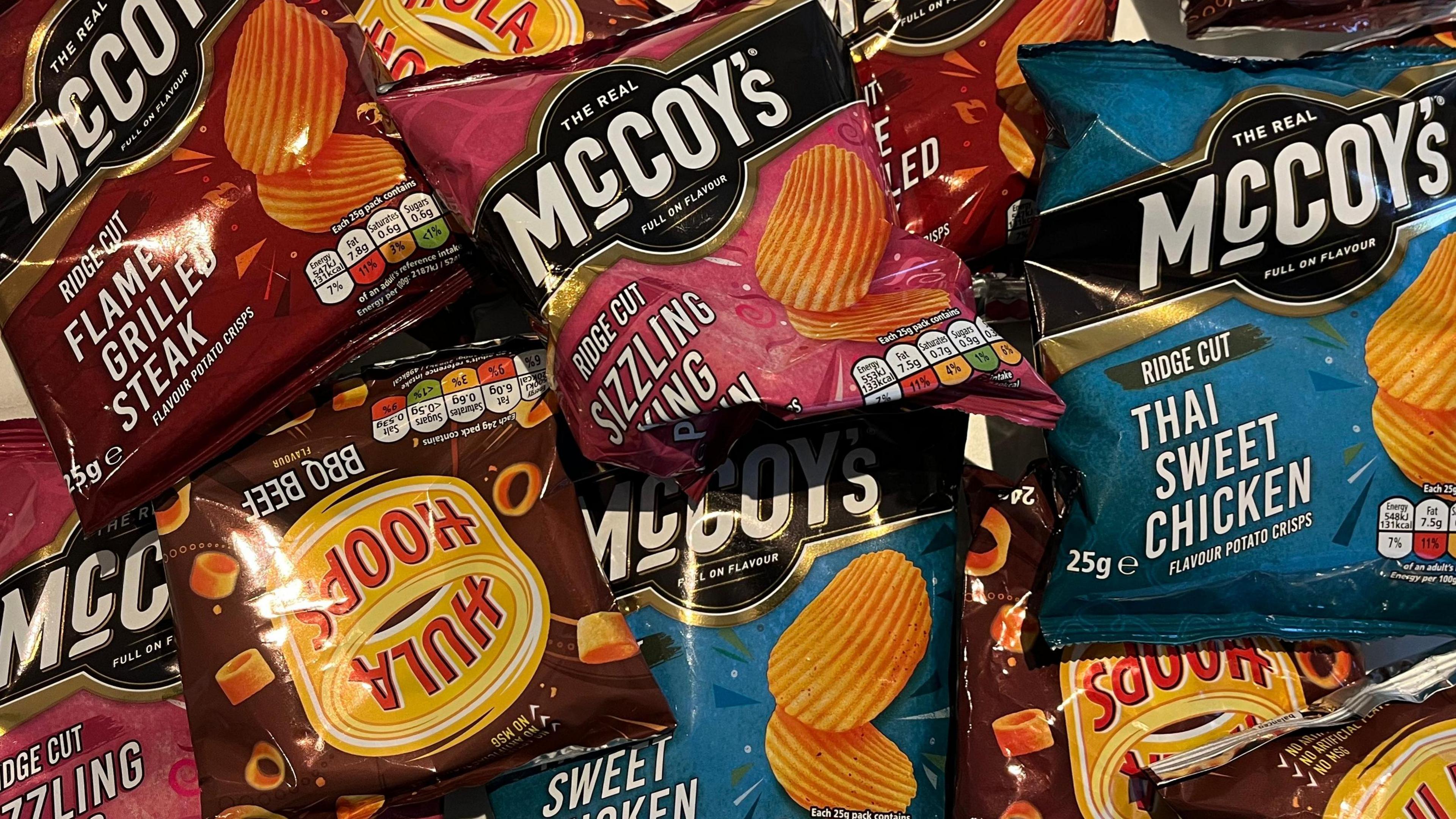 Packets of McCoy's and Hula Hoops crisps sit on a table.
