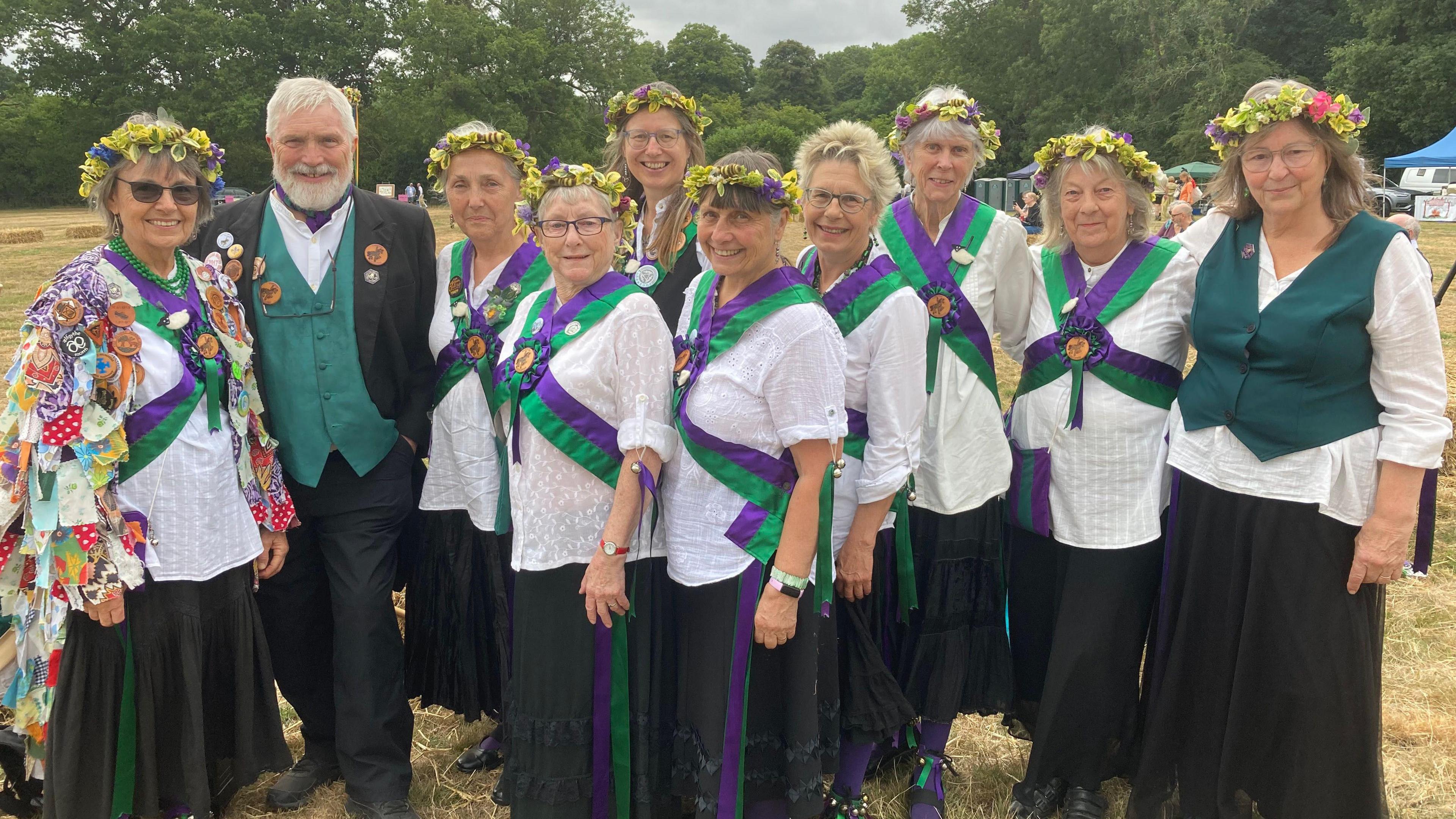 Groupe of Morris dancers - men and women wearing white shits with green and purple sashes.