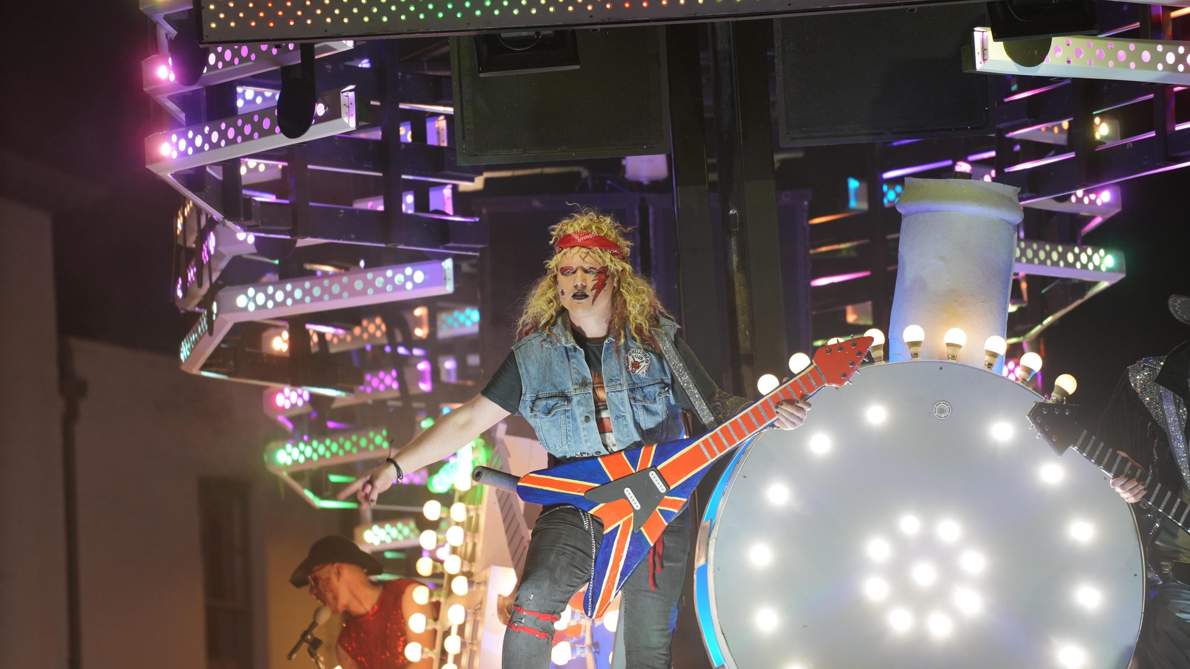 Man dressed as a rock star with guitar on a carnival cart