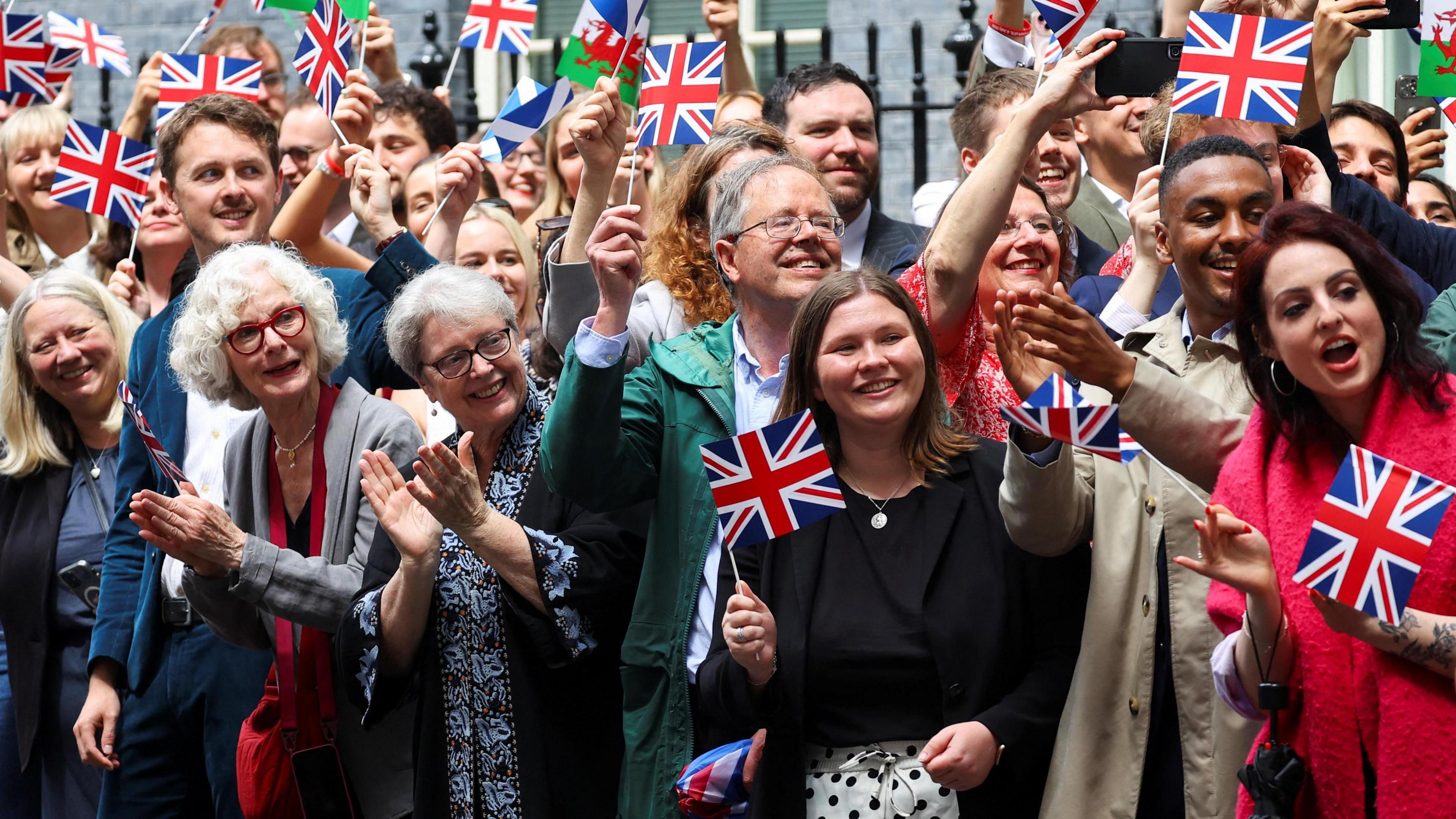 Dozens of smiling Labour supporters wave flags and look on as Keir Starmer makes his way to Downing Street for the first time as prime minister.