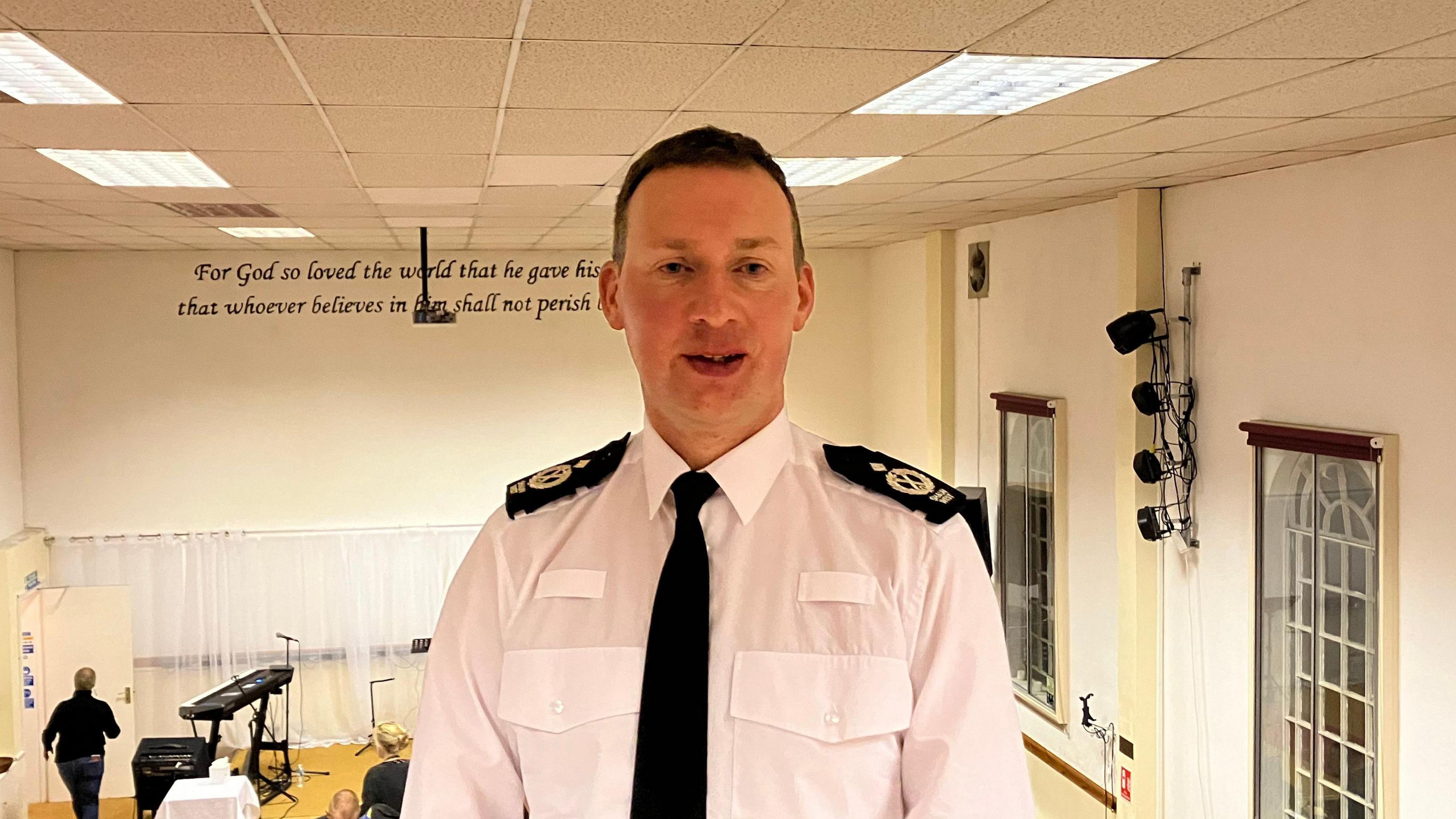 Deputy Chief Constable Shaun West stood in uniform at an indoor music event.