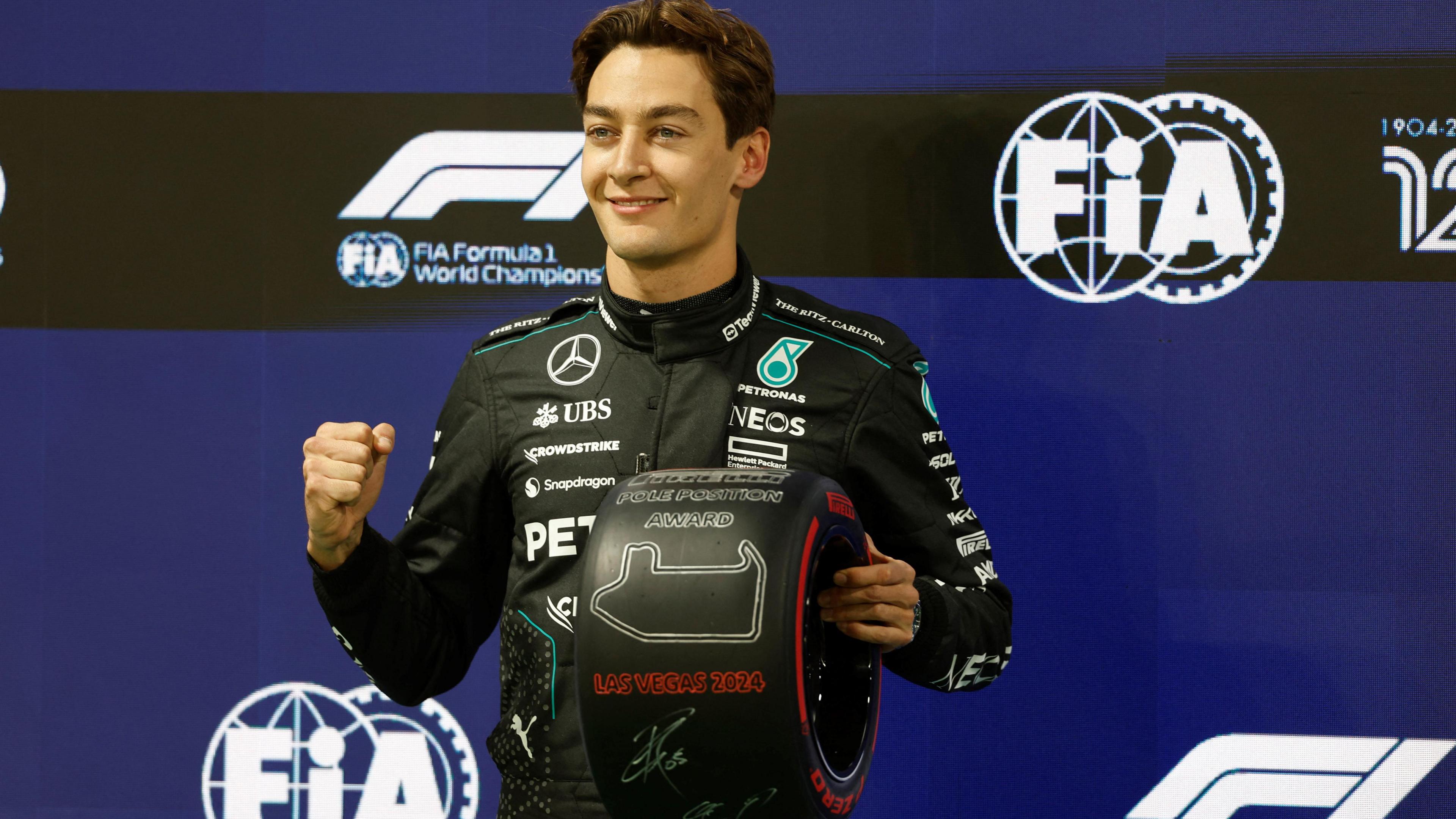 George Russell holds the pole position award and clenches his right fist in celebration