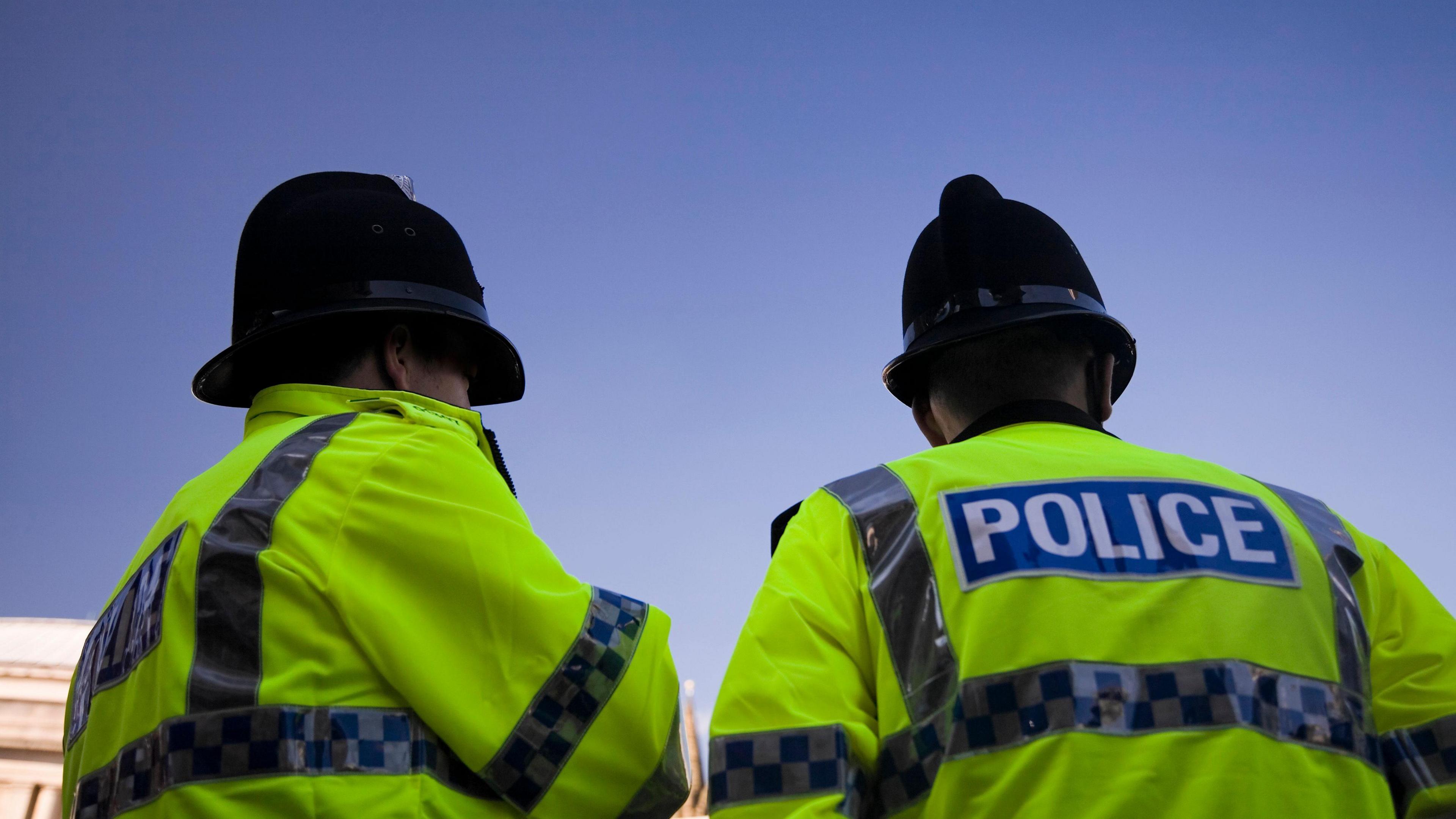 A stock image of two police officers in uniform pictured from behind