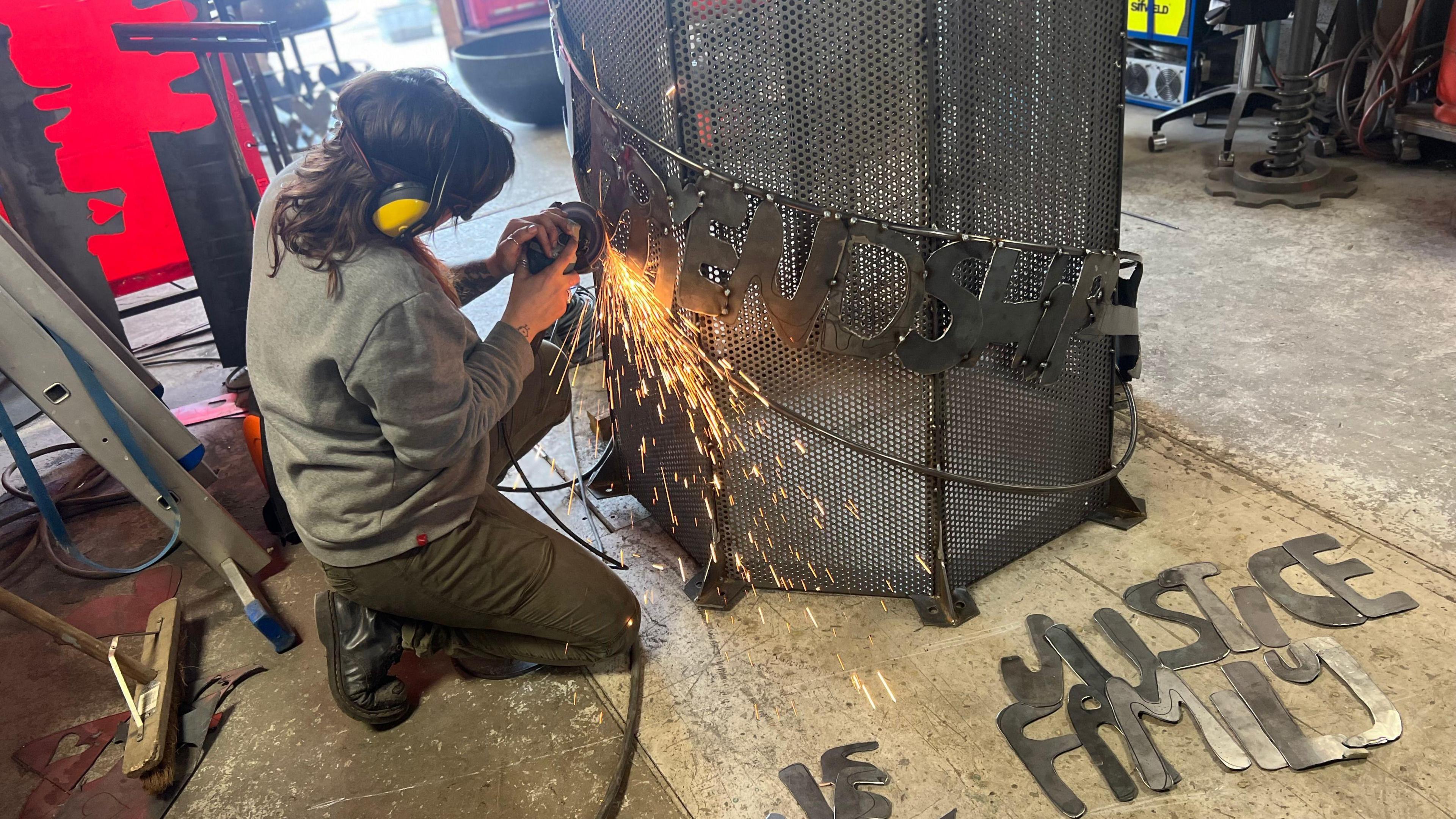 Woman putting metal words onto the Beacon of Hope Sculpture