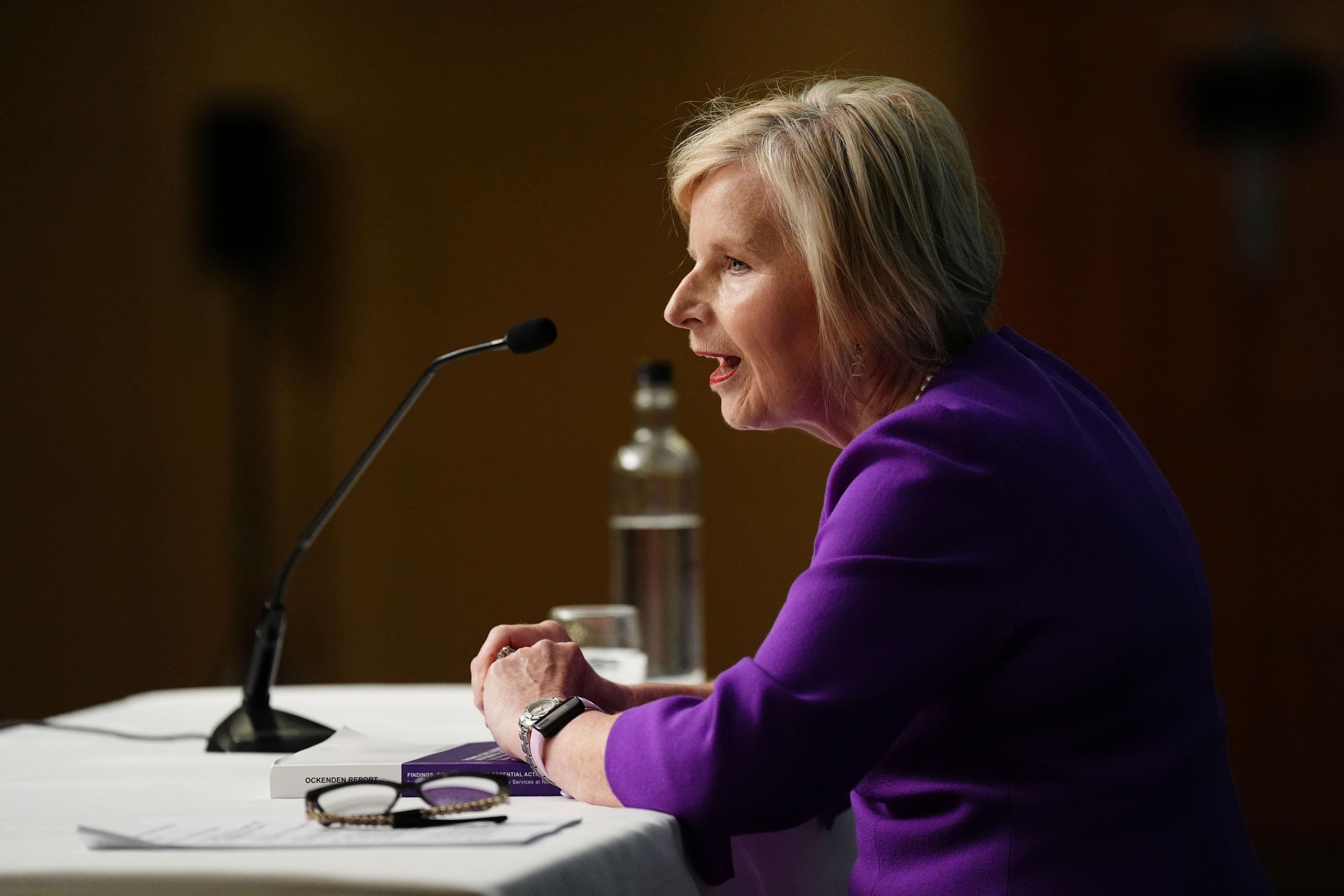 Donna Ockenden, wearing purple, speaks into a microphone.