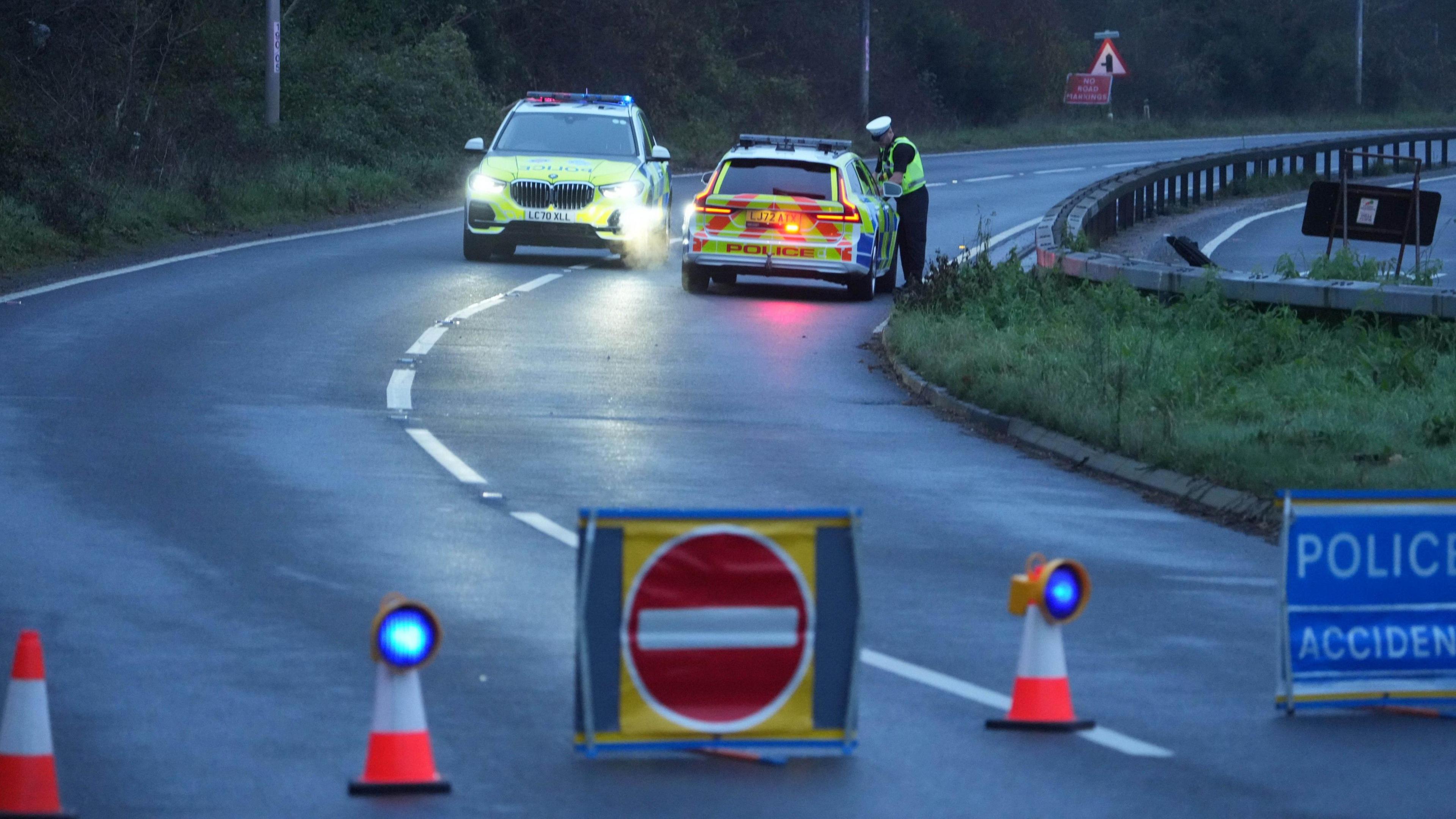 Two police cars parked on the A27 at Fontwell near Arundel, with cones and a no entry sign sealing off the carriageway to traffic. A traffic officer leans into the window of one of the cars.