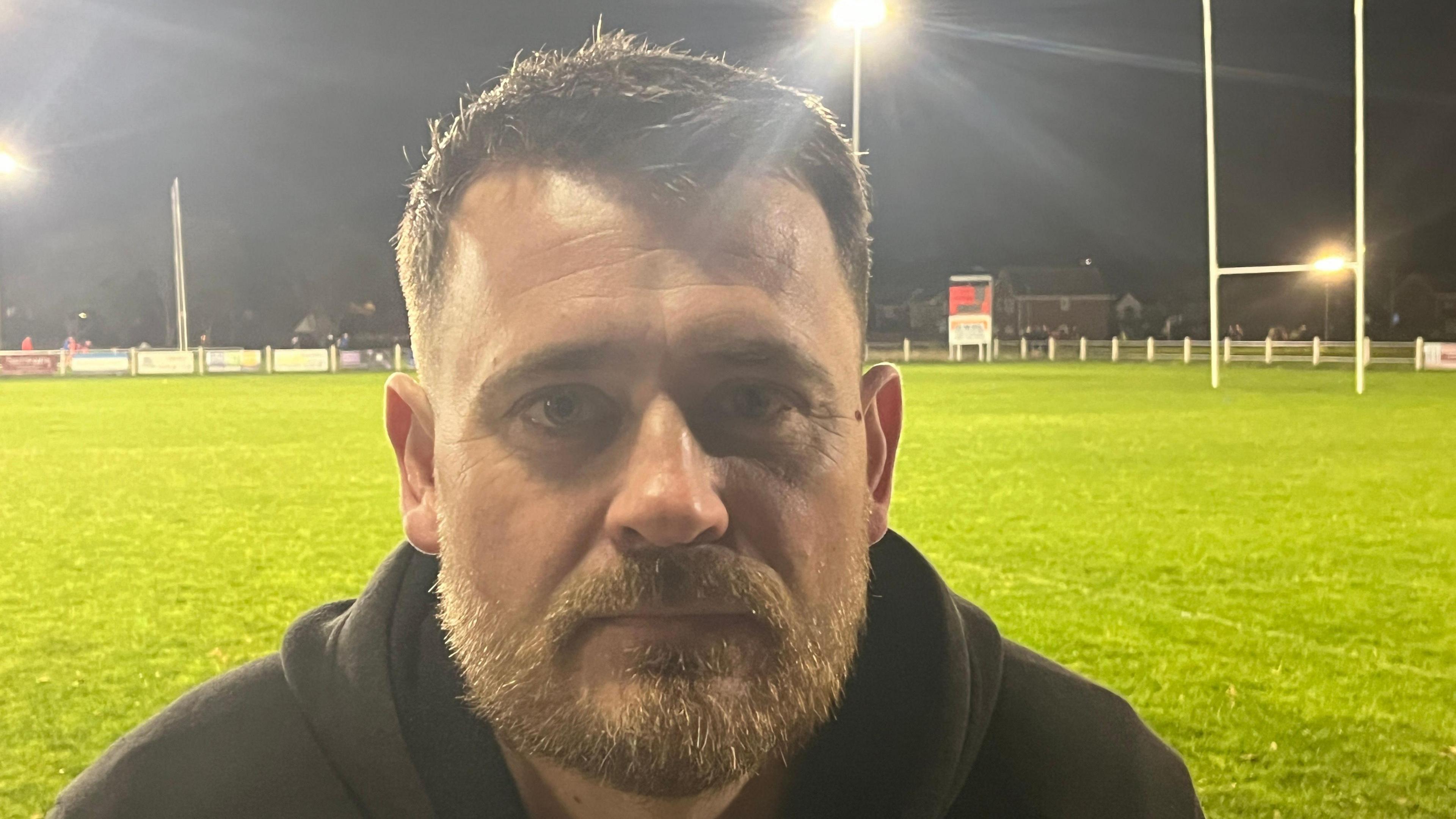 Rhyl rugby player Ashley Bishop sitting next to the pitch at Rhyl Rugby Club