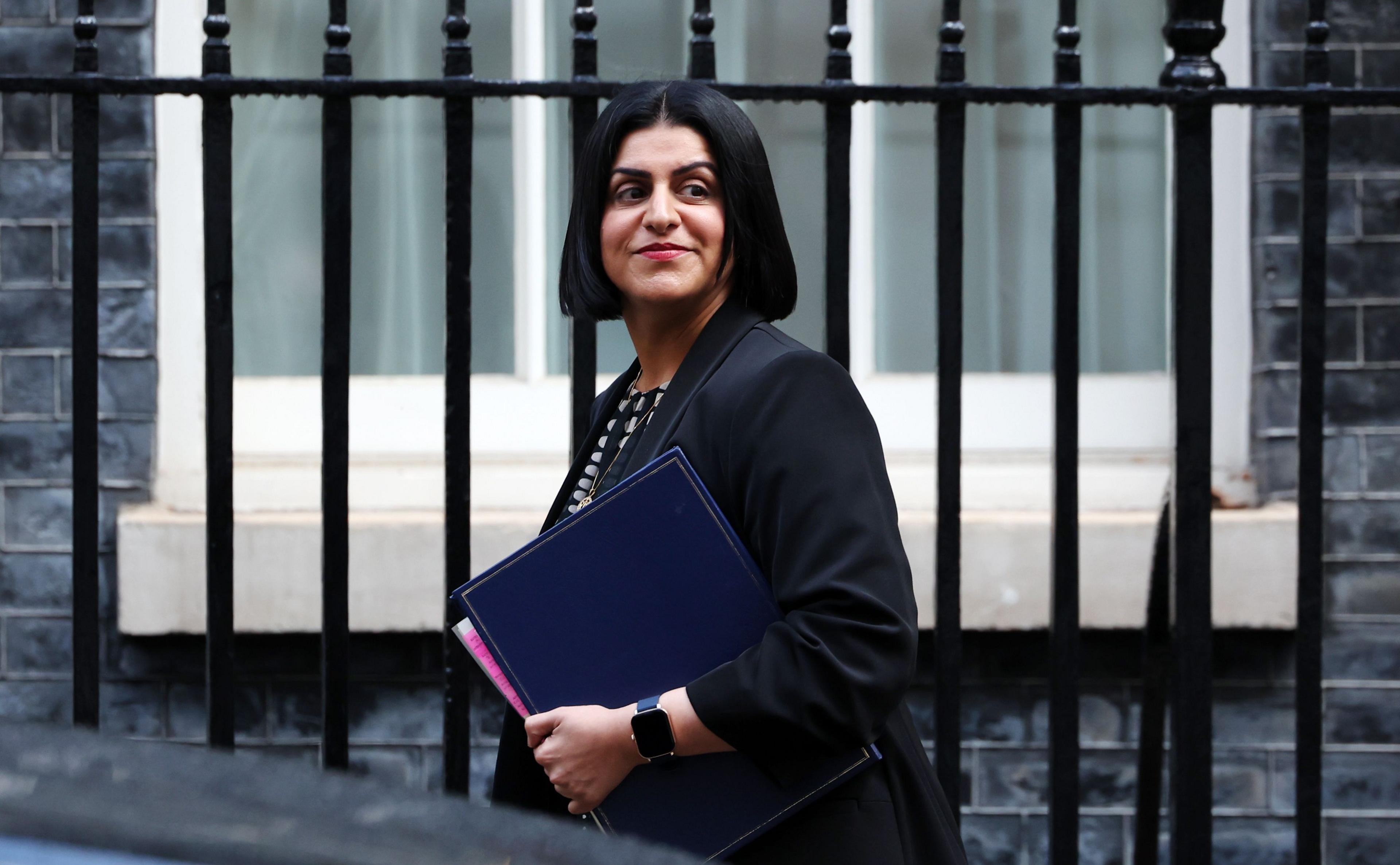 Shabana Mahmood carrying documents outside a building with railings