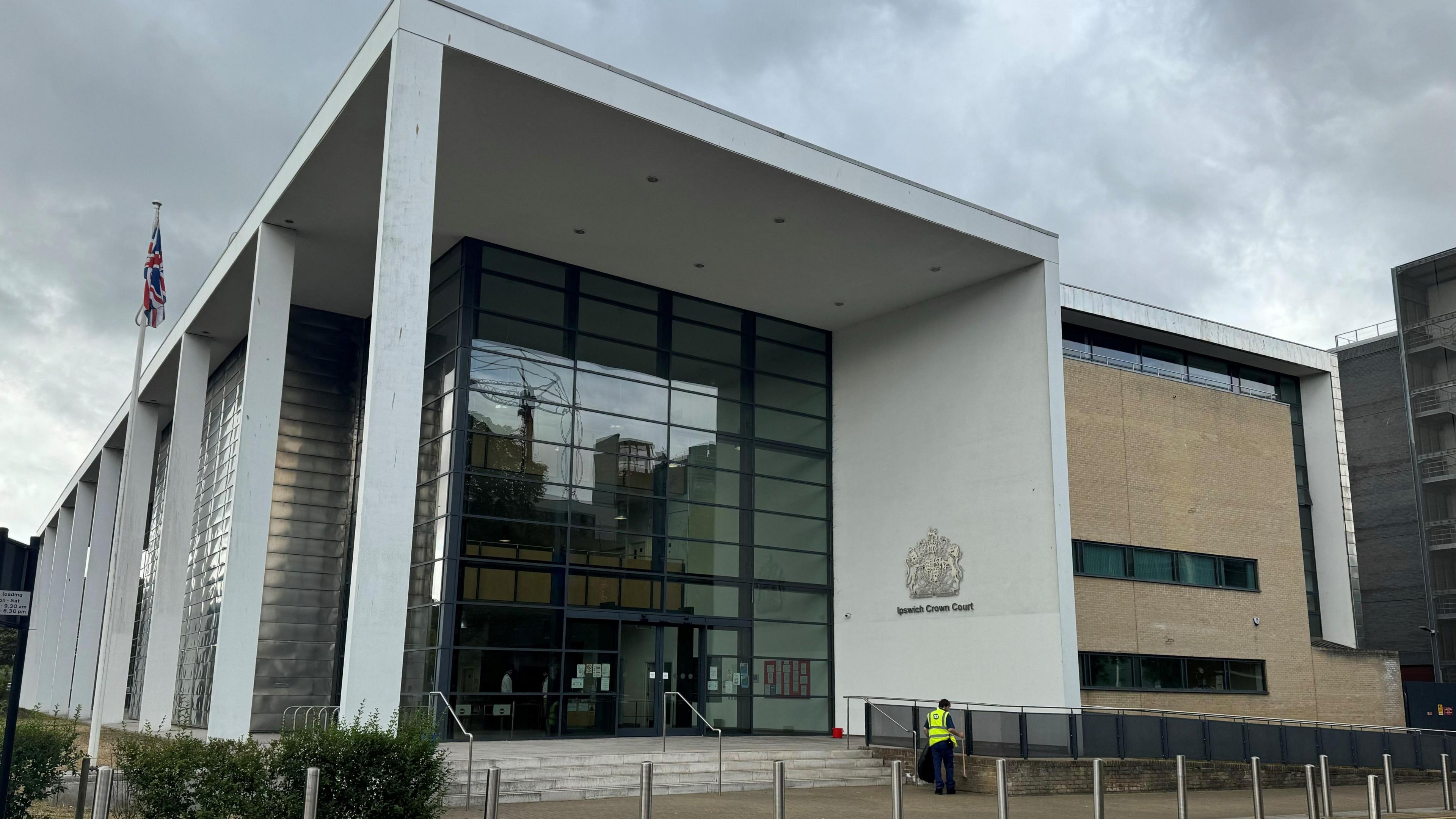 Ipswich Crown Court. The concrete and glass frontage can be seen, as can the emblem of the court on one of the walls.