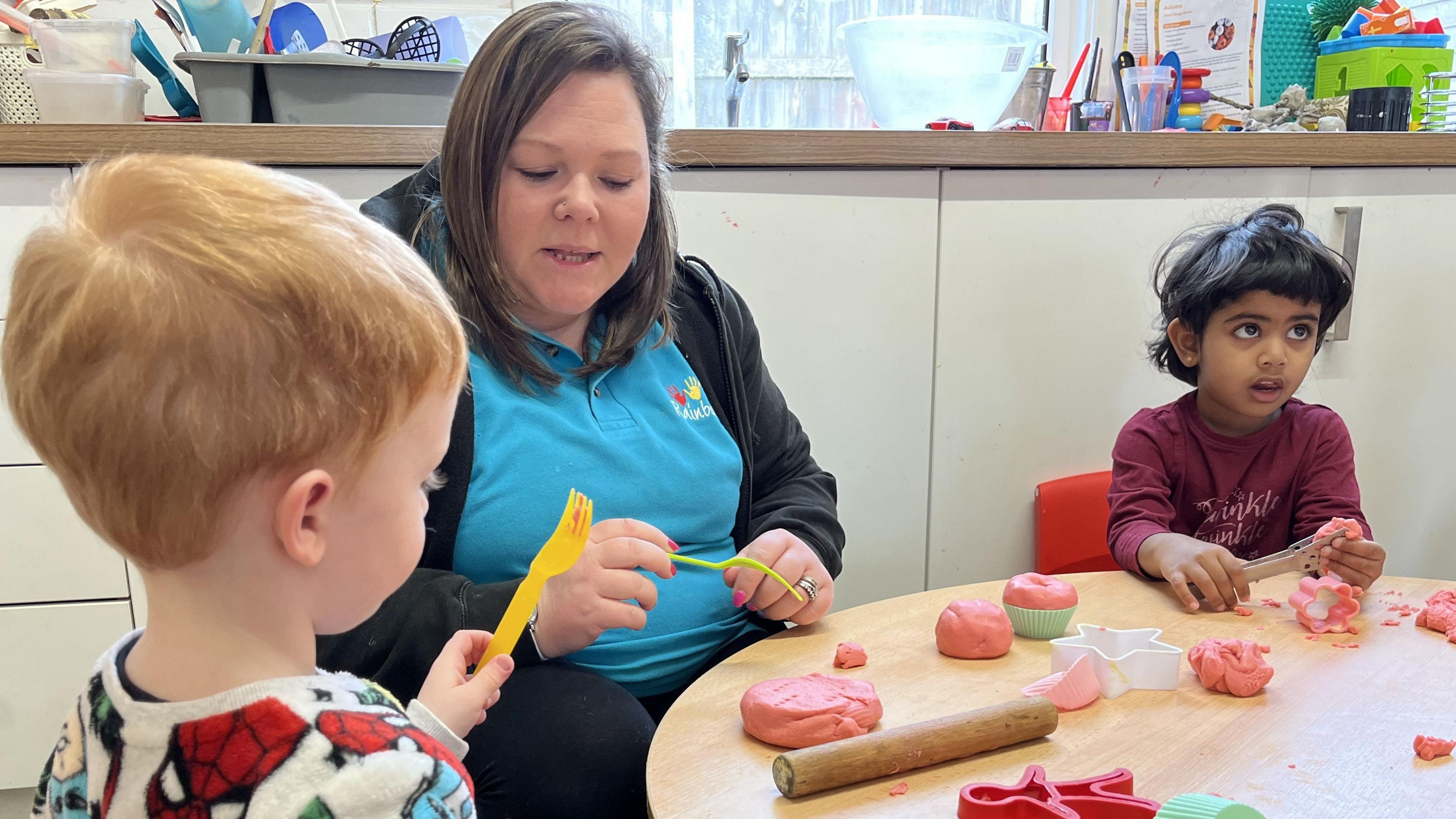 Children playing with playdough under the guidance of a Rainbow Early Years staff member