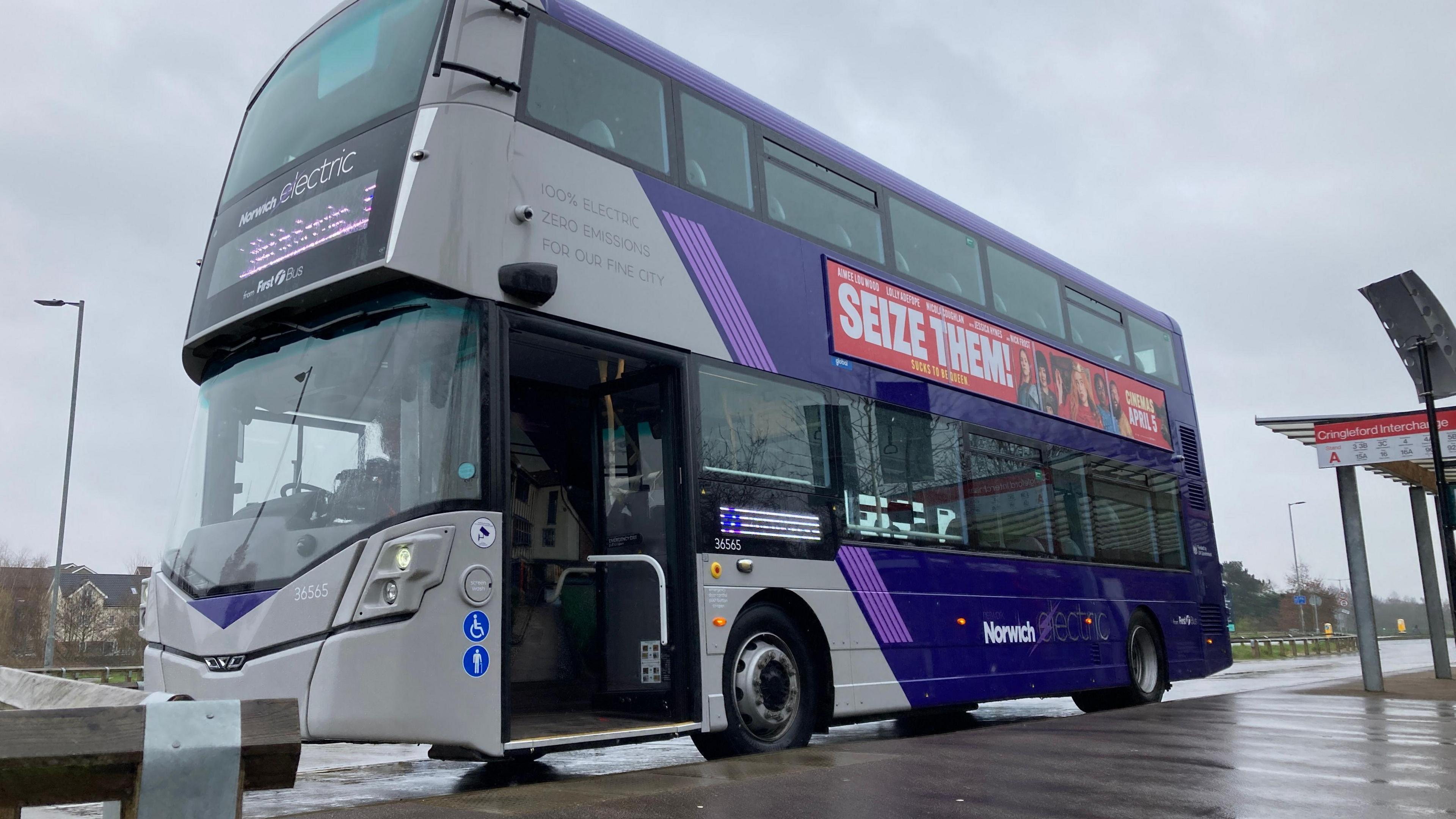 An electric double-decker bus parked at a bus stop