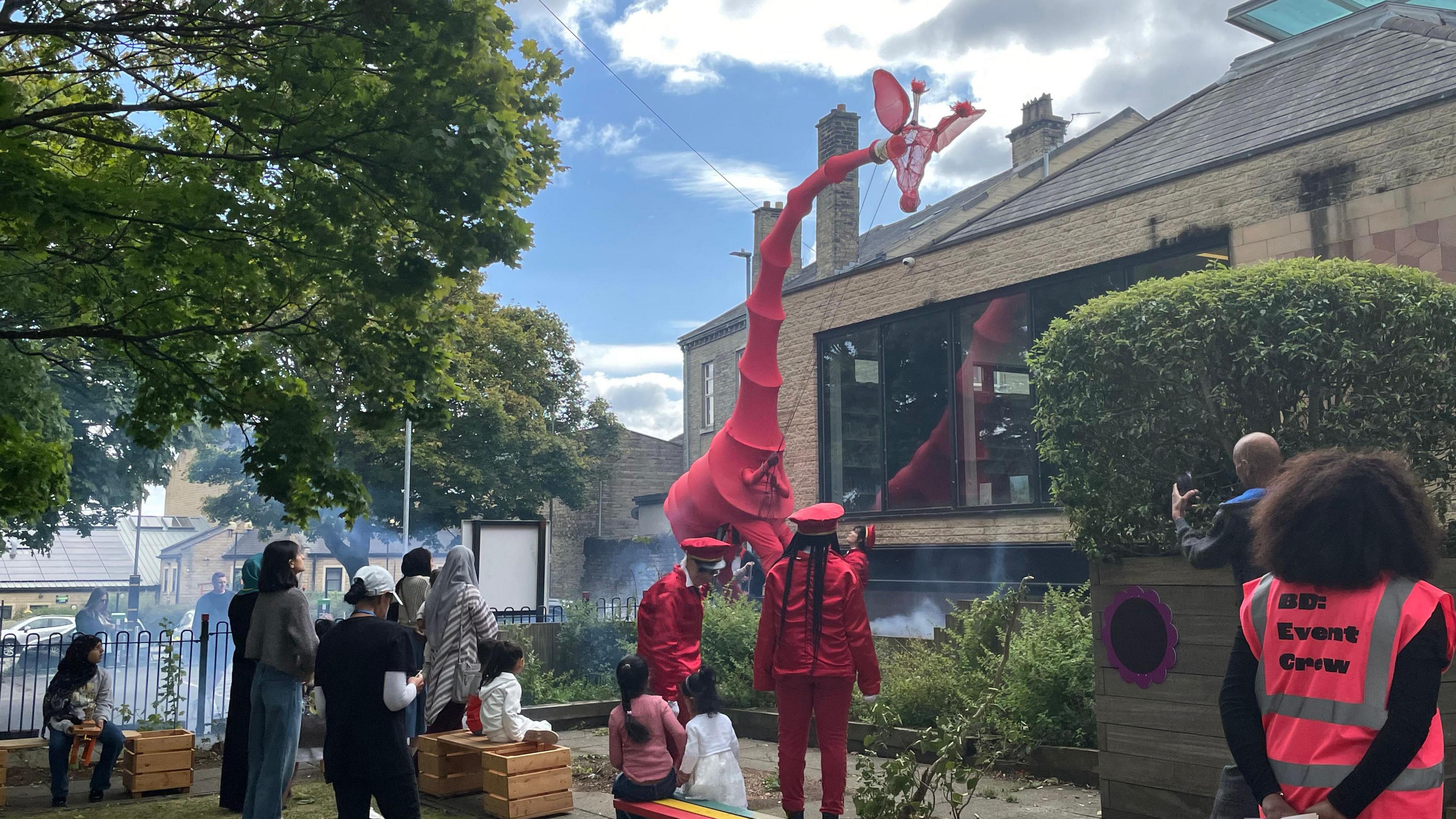 People looking up at a giraffe puppet at a library in Bradford