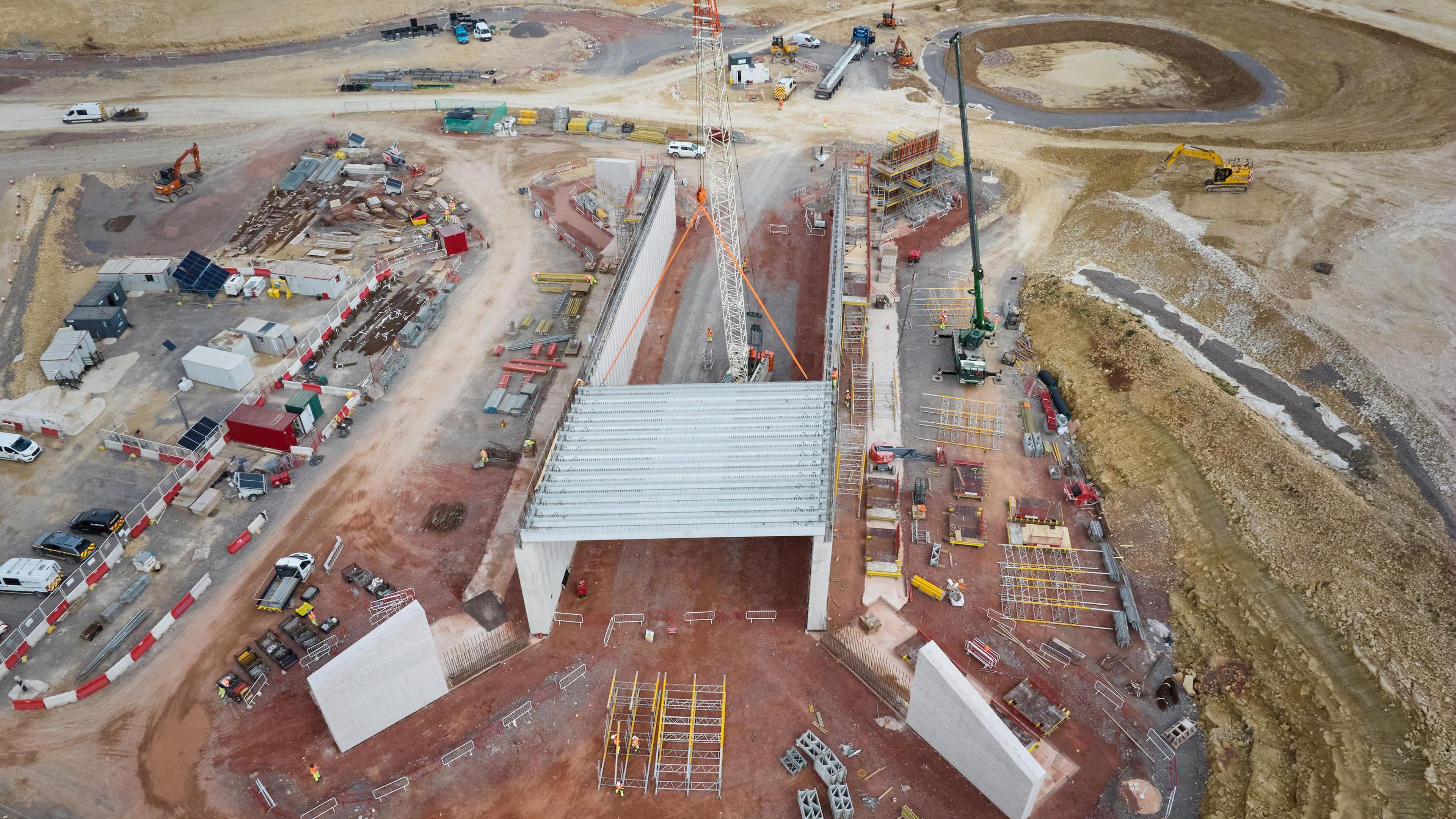A photo taken from the air showing construction work taking place, with machinery, a crane and a concrete structure with beams