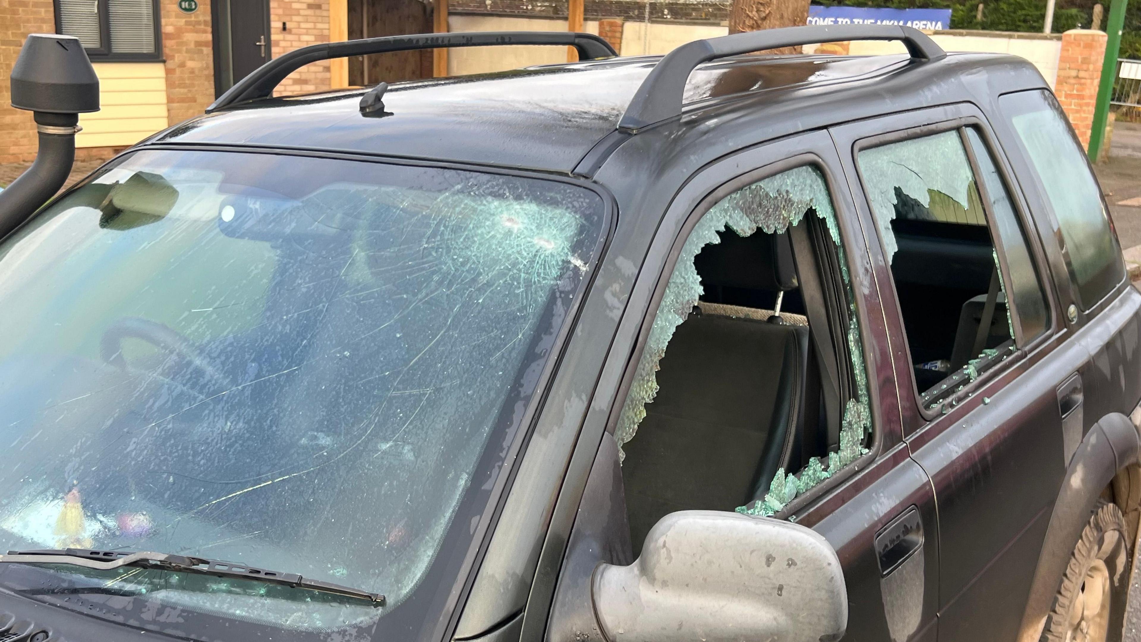 A black Land Rover with smashed side windows and a smashed front windscreen