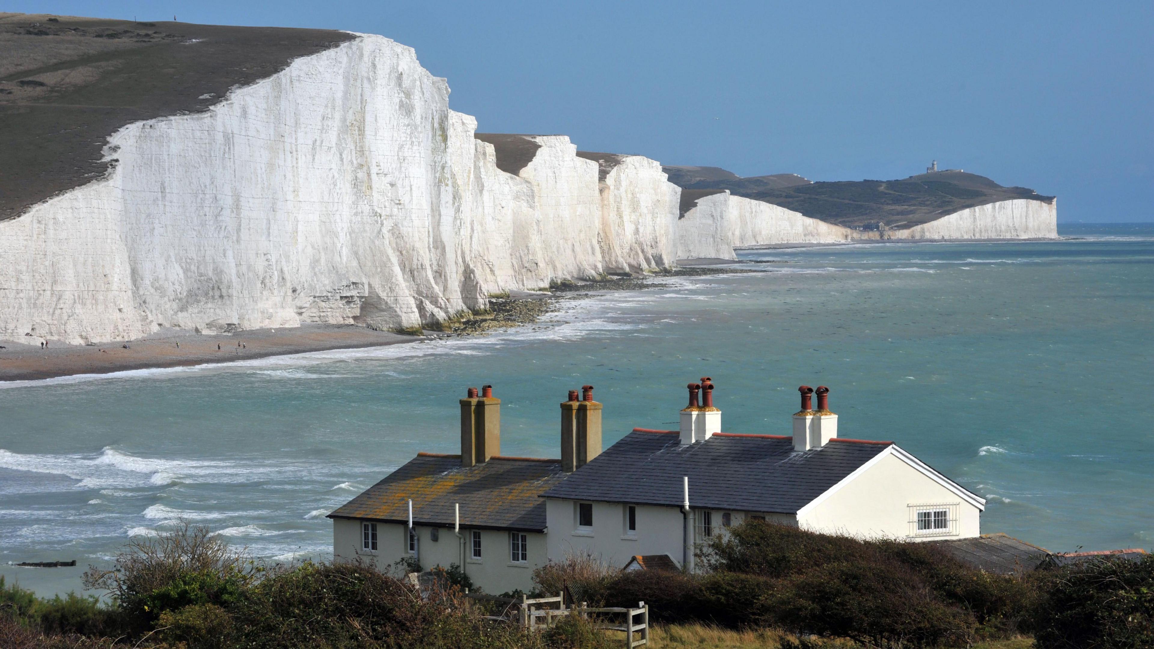 The Seven Sisters cliffs in East Sussex, large white chalk cliffs which rise and fall creating seven mounds hence the name Seven Sisters. The coast guard cottages which sit near a cliff edge also sit in the foreground looking over the sea