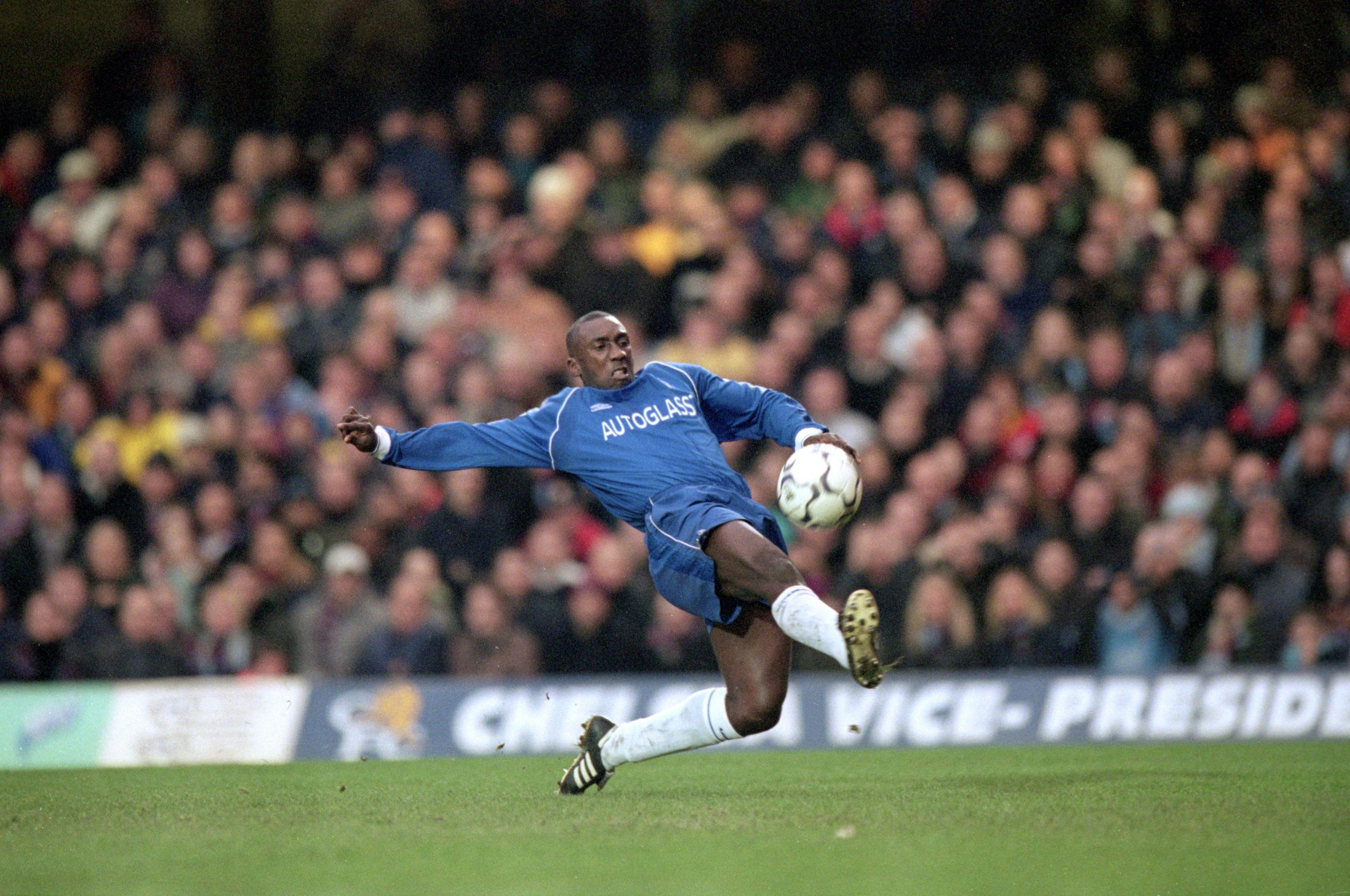 Jimmy Floyd Hasselbaink stretches to kick the ball while wearing a Chelsea kit