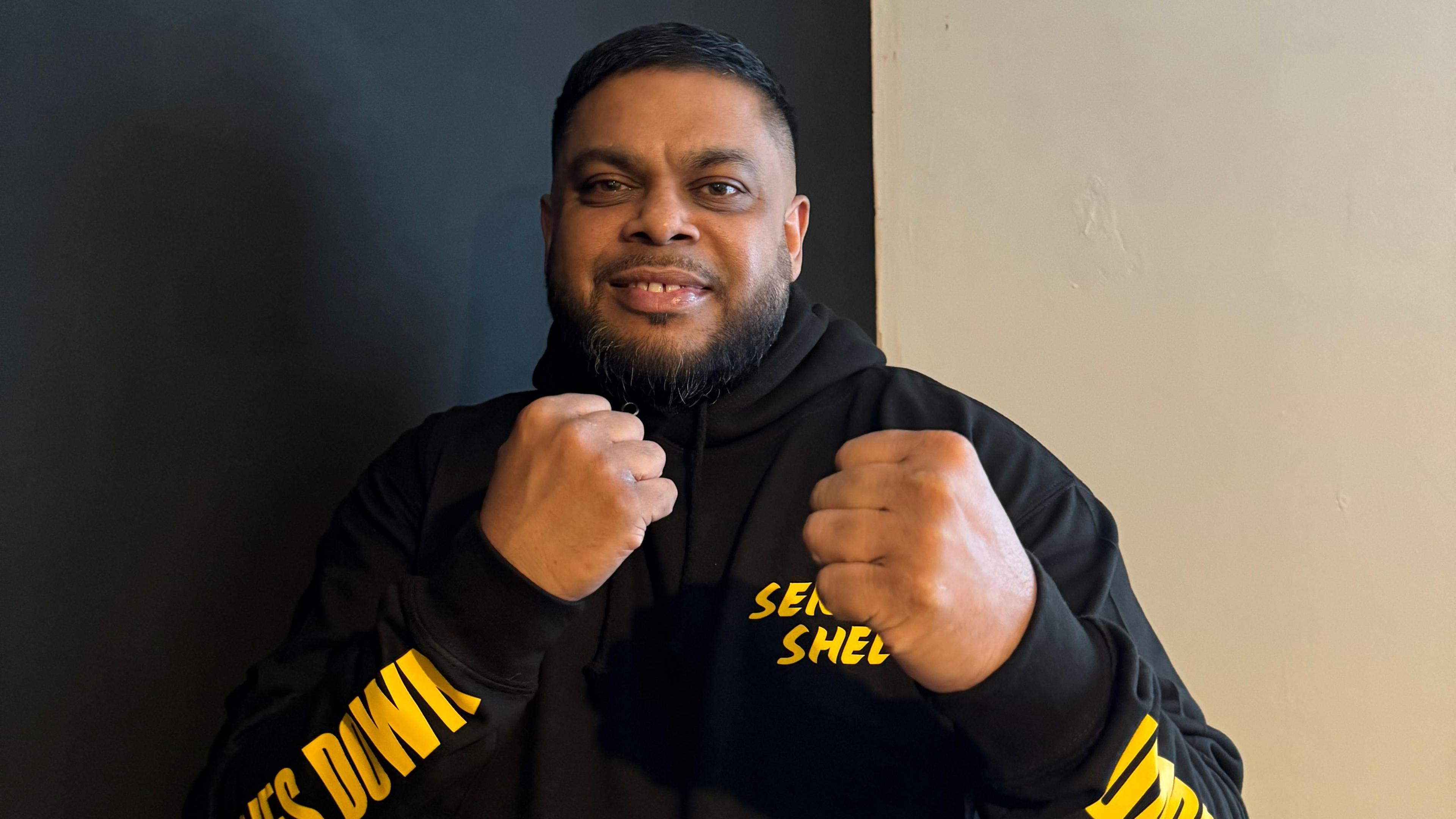 Shelim Ali. He is doing a karate pose, holding both his fists up. He is looking directly at the camera and smiling