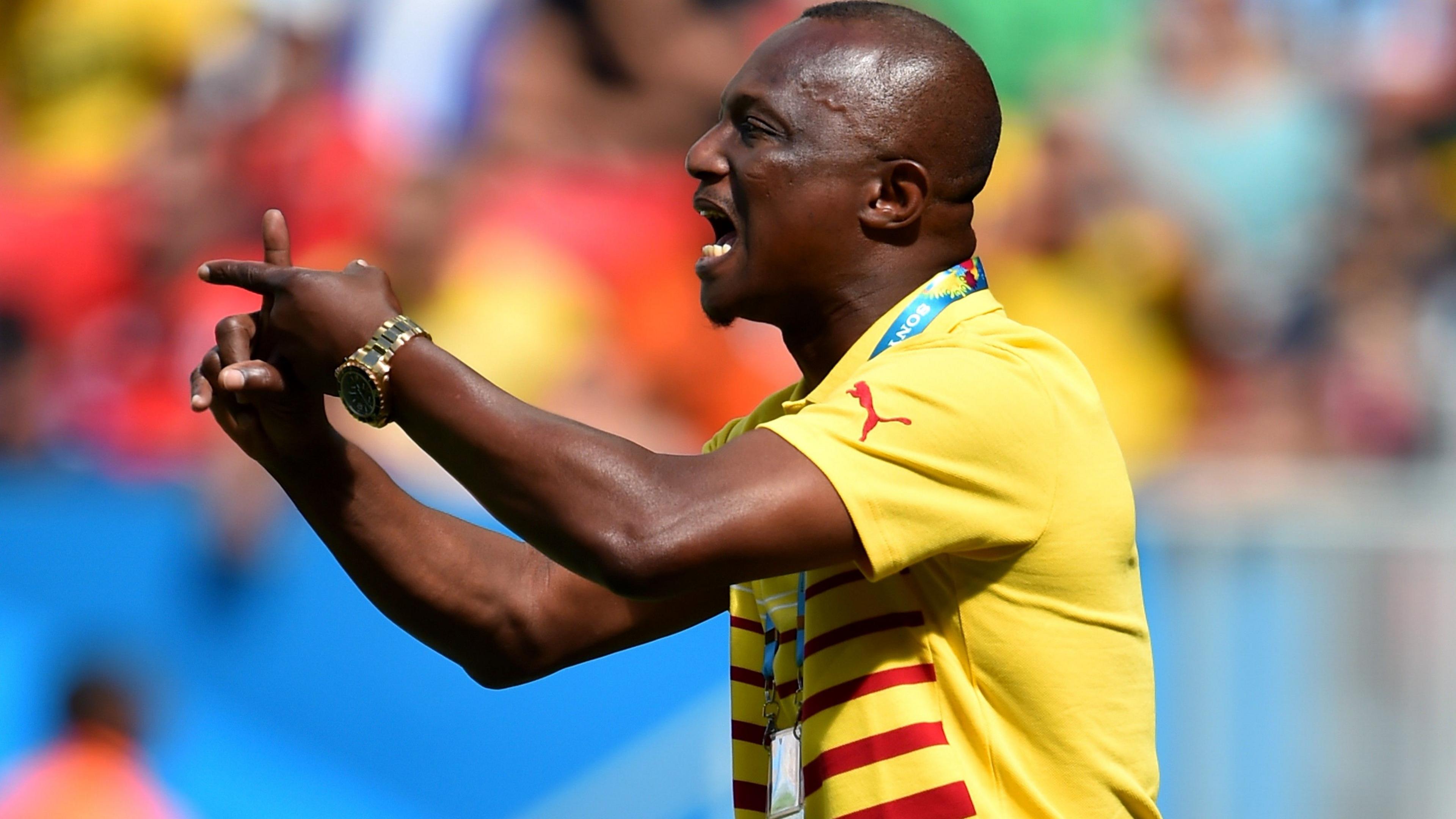 Kwasi Appiah, wearing a yellow Ghana polo shirt with red stripes on the front, crosses his index fingers as he gestures during the 2014 Fifa World Cup Group G match between Portugal and Ghana in Brazil