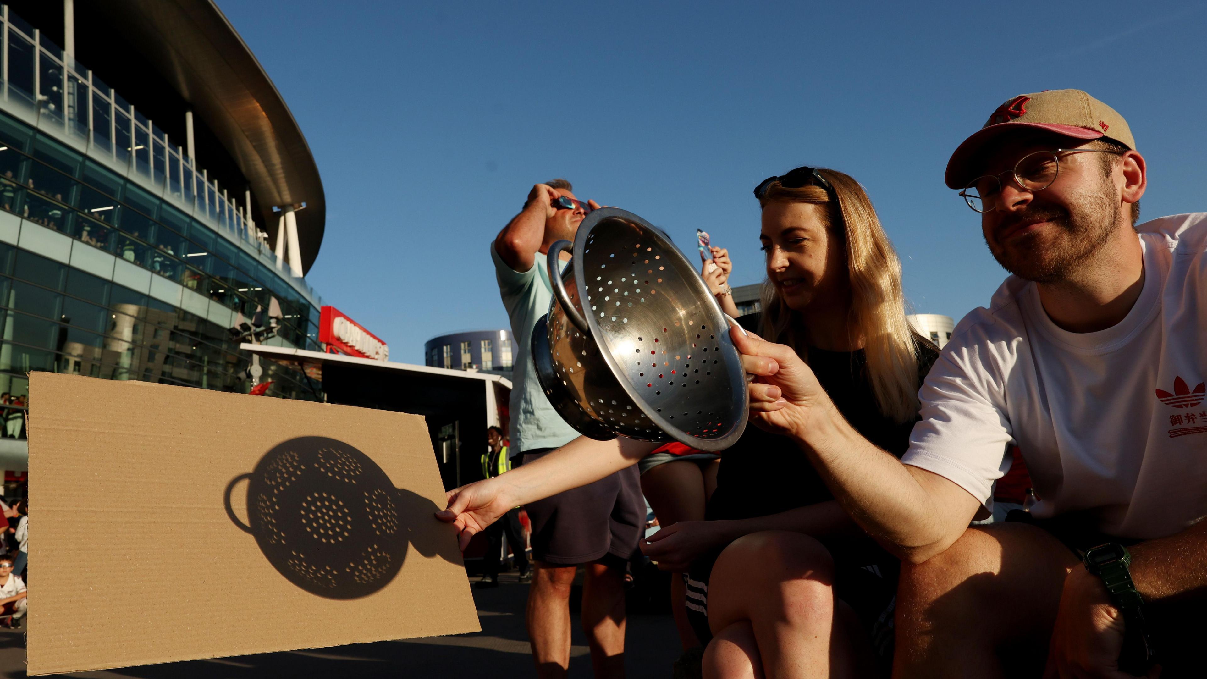 Arsenal fans use cardboard and a colander to try and see the solar eclipse before their side's pre-season friendly against Como