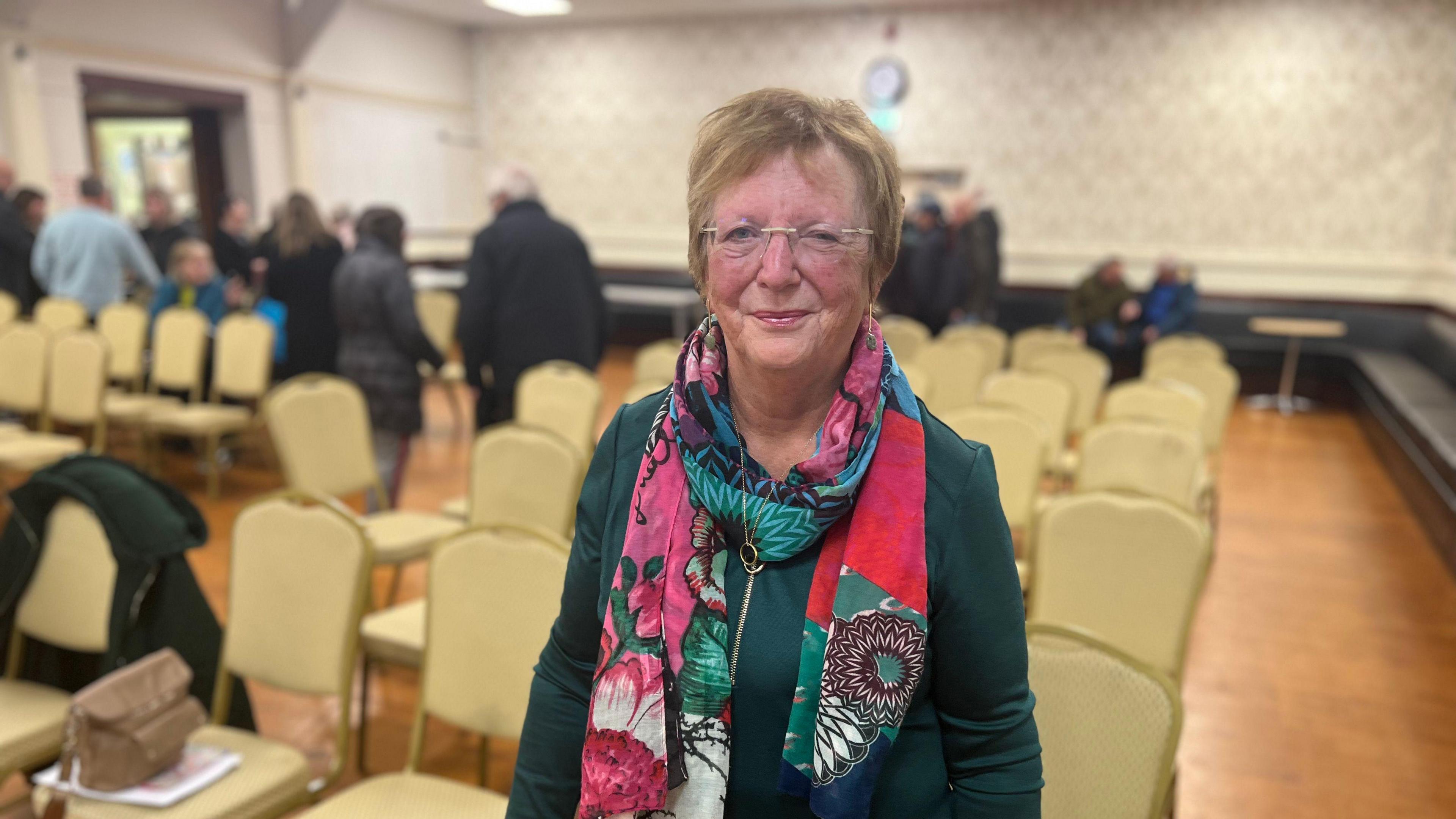 Woman in glasses green top and printed scarf 