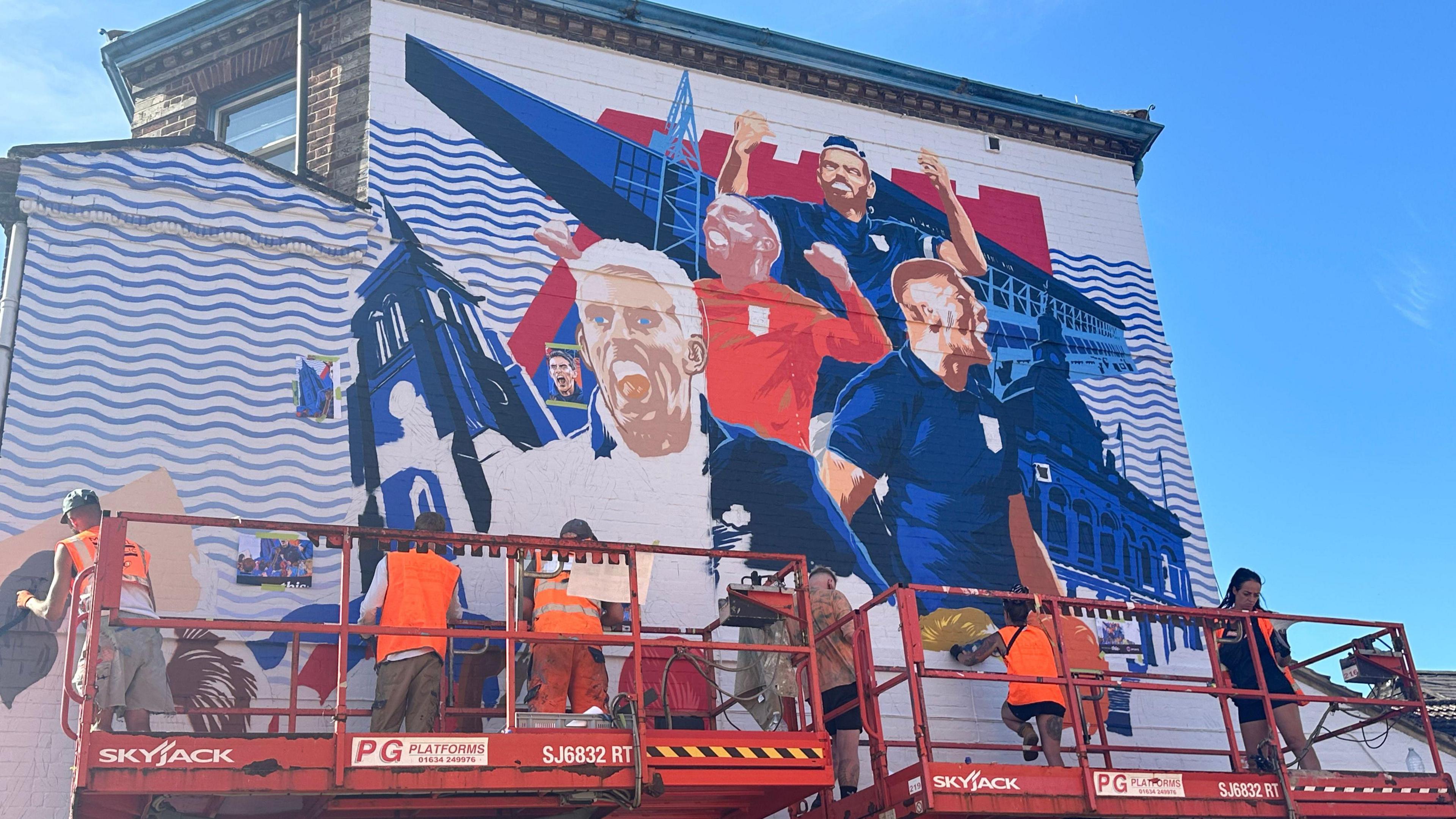 Painters at work on the Ipswich Town mural at the bottom of Barrack Lane