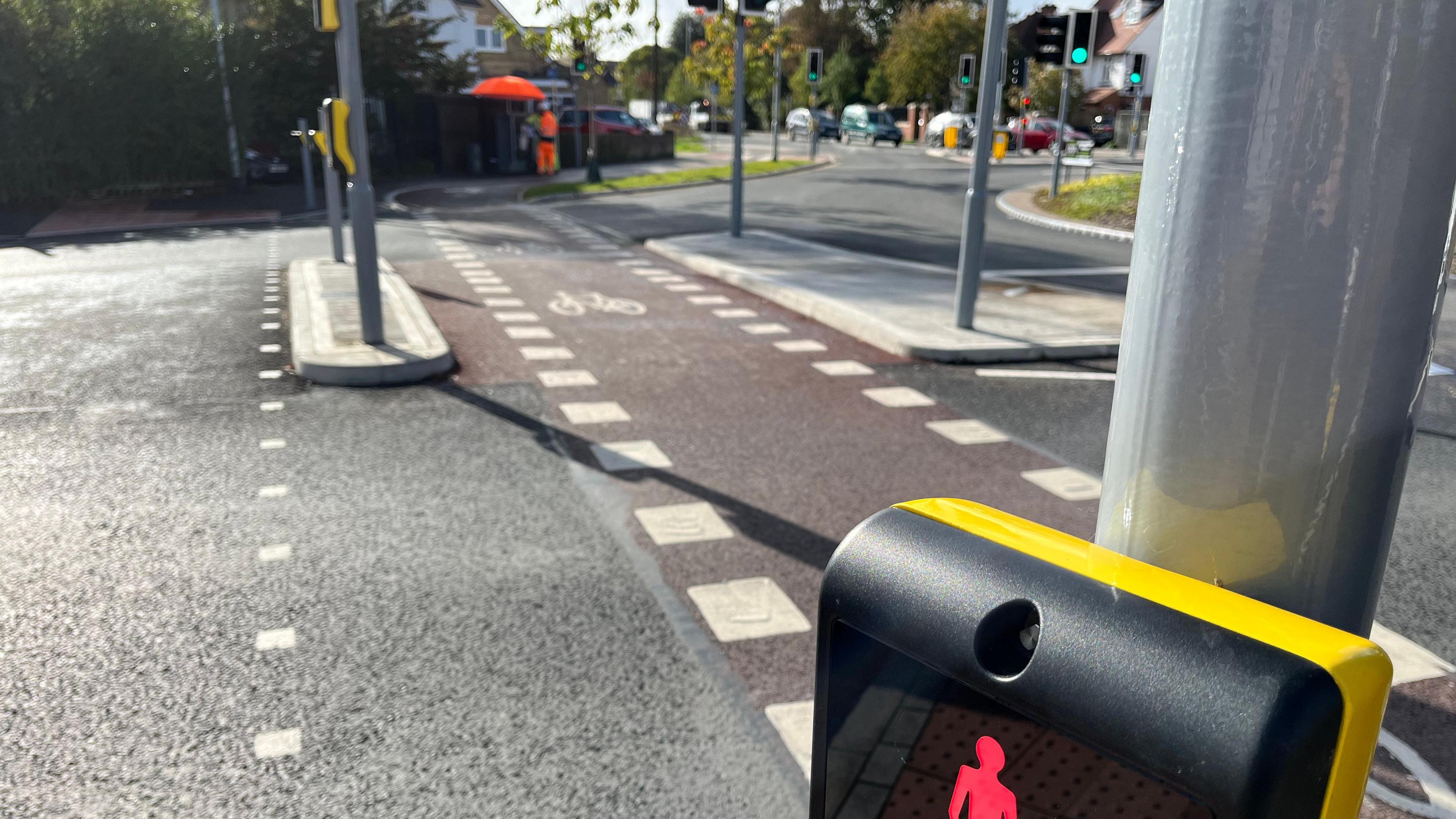 A close up of a sparrow junction on the roundabout in Cambridge, with white markings on a road and houses and greenery in the background.